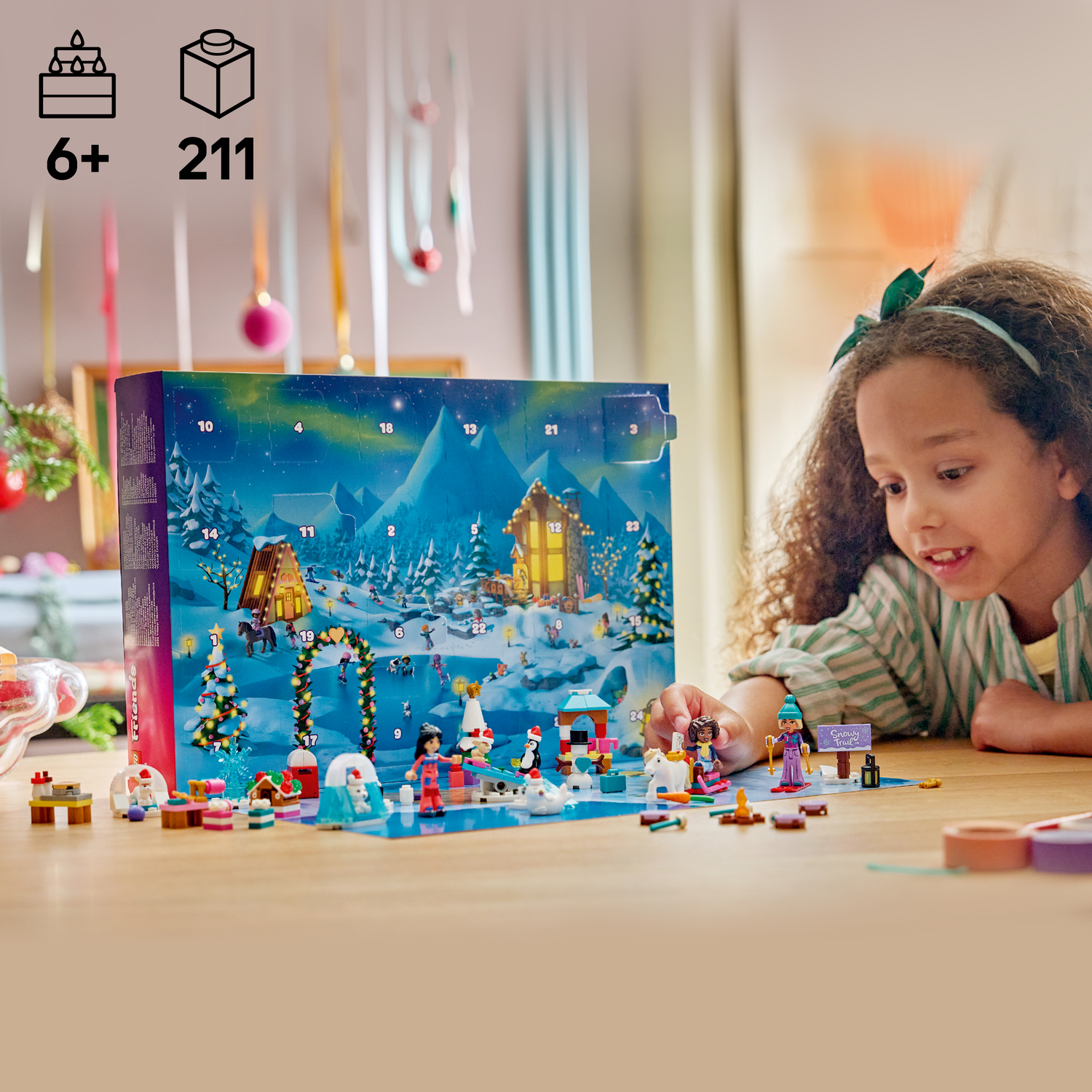 Une fille regarde un calendrier de l'Avent Lego représentant une scène de village hivernal avec de nombreuses petites figurines.