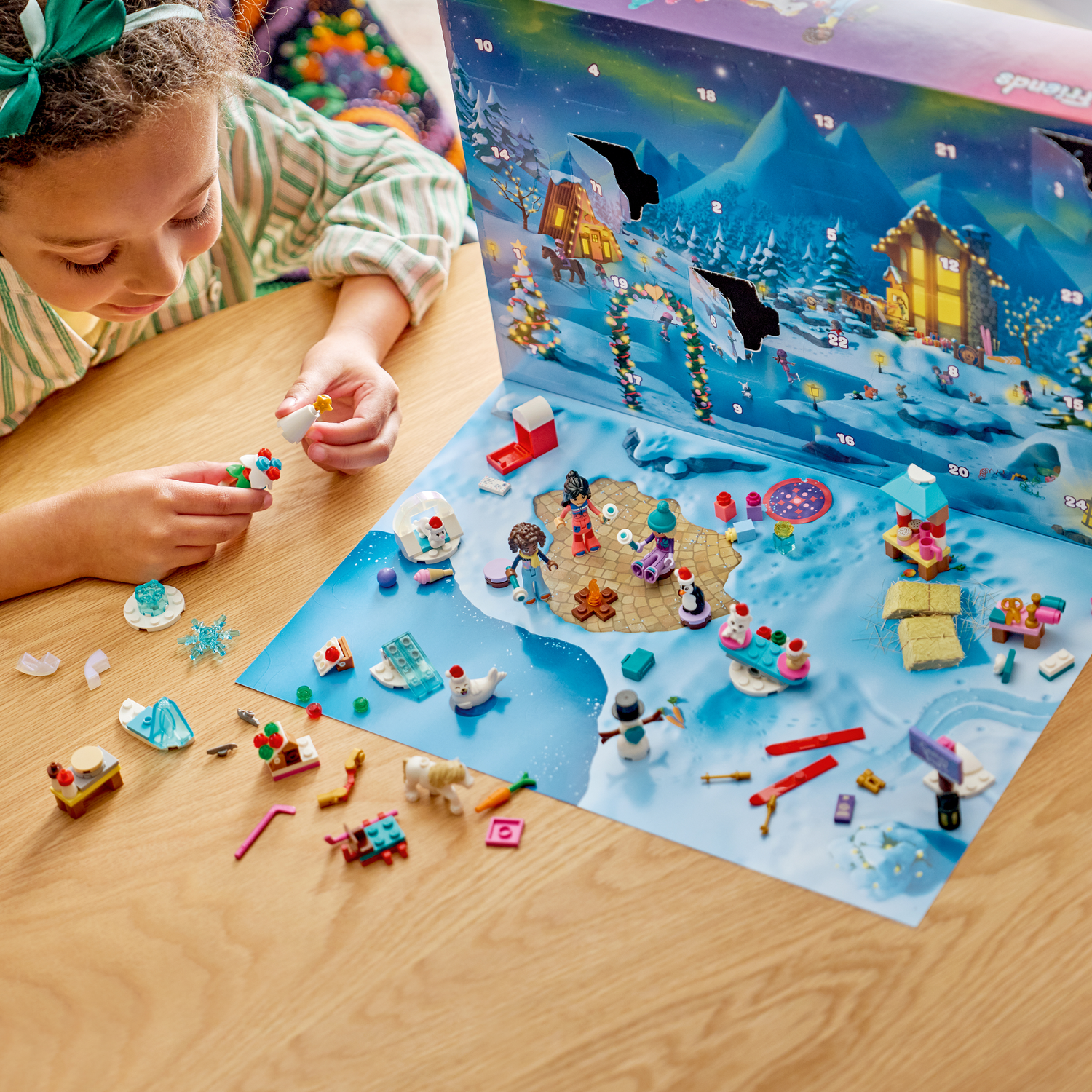 Une fille joue avec un calendrier de l'Avent Lego, construisant une petite figurine avec un haut blanc et une étoile.