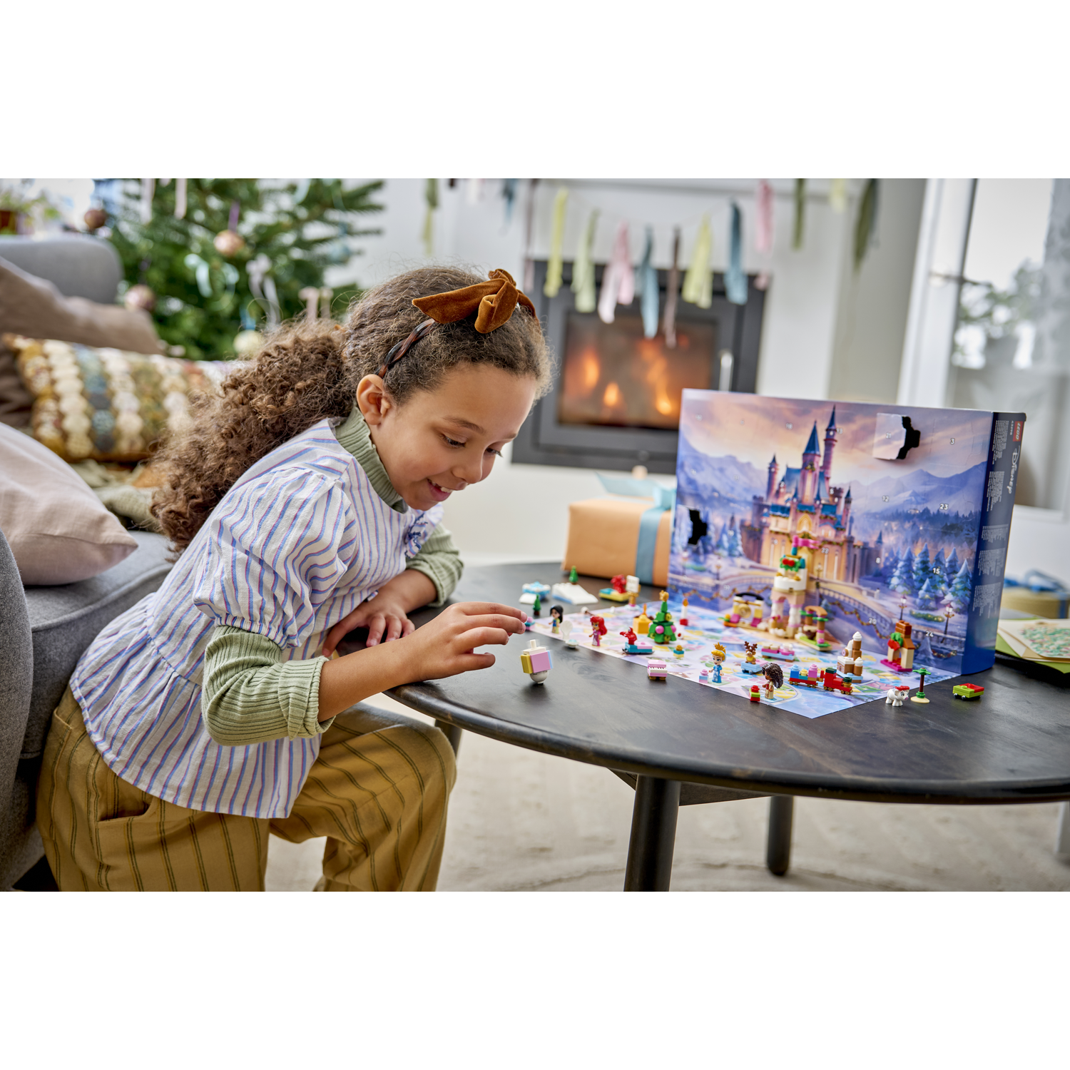 Une fille joue avec un calendrier de l'avent Lego représentant un château sur une table.