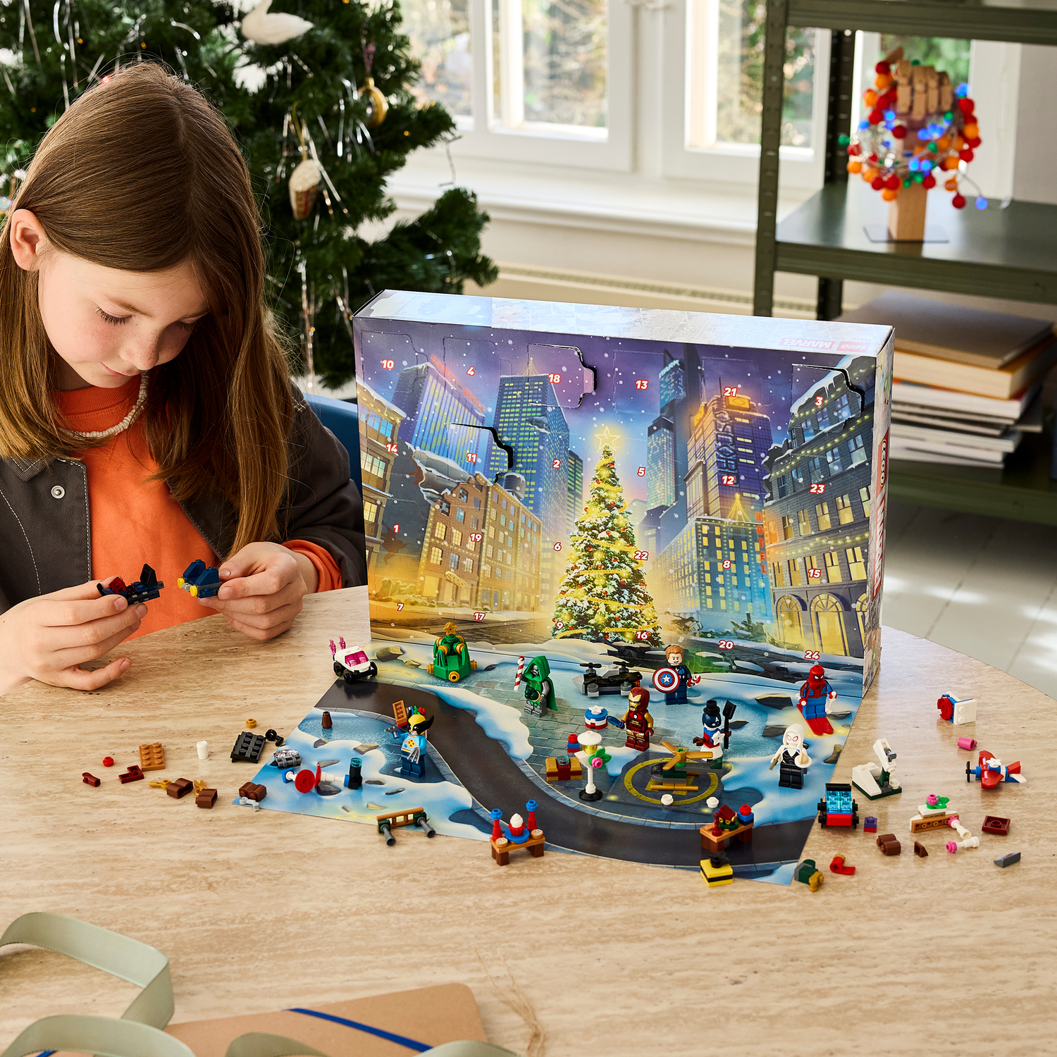 Une fille construit des figurines Lego devant un calendrier de l'avent de Noël sur le thème de Marvel.