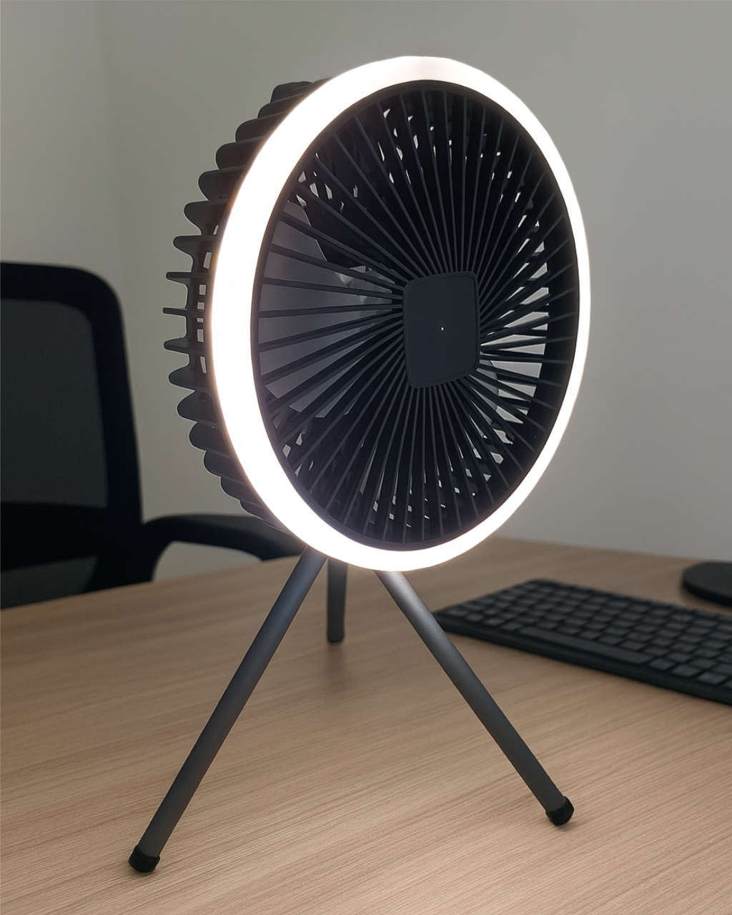 Egy fekete gyűrűs ventilátor LED-fénnyel állványon asztalon.