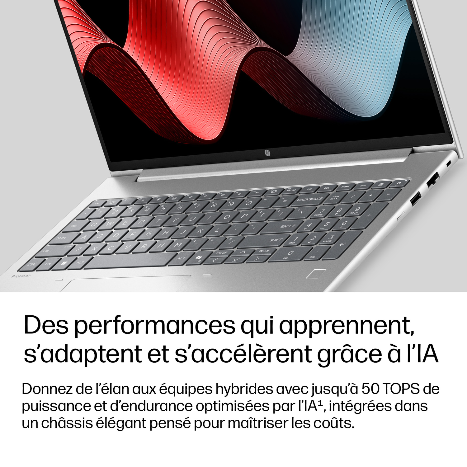 Un ordinateur portable argenté avec clavier et écran affichant un motif abstrait.