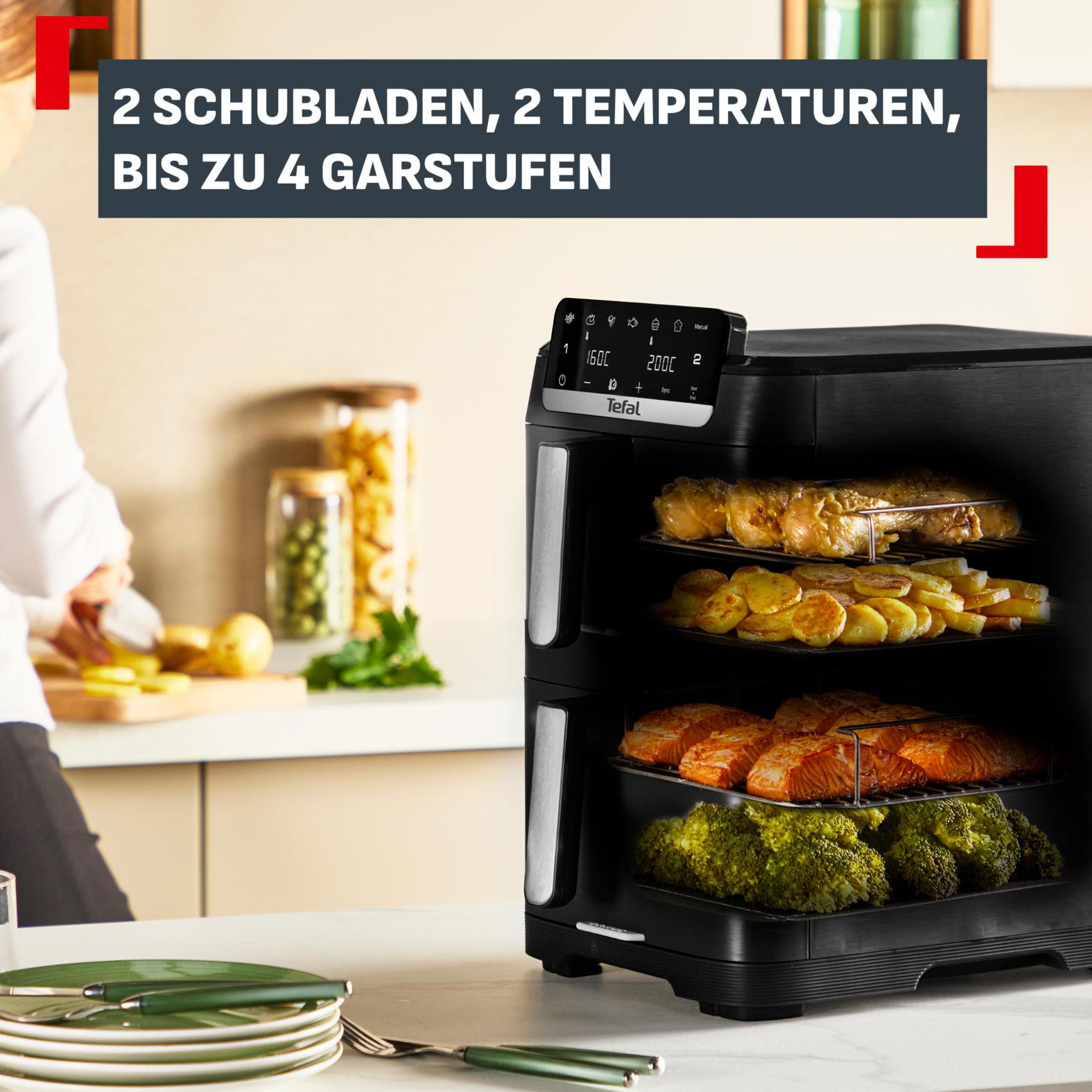 Ein schwarzer Tefal Heißluftofen mit Hähnchen, Kartoffeln, Lachs und Brokkoli.