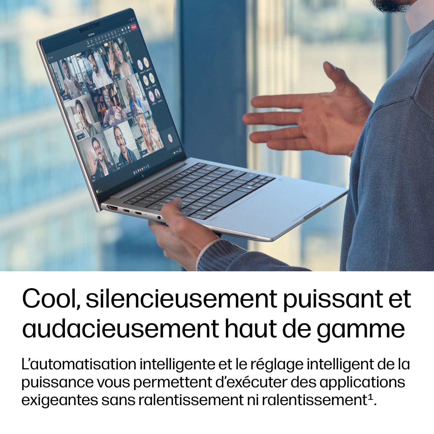 Un homme tient un ordinateur portable montrant un appel vidéo avec plusieurs personnes.