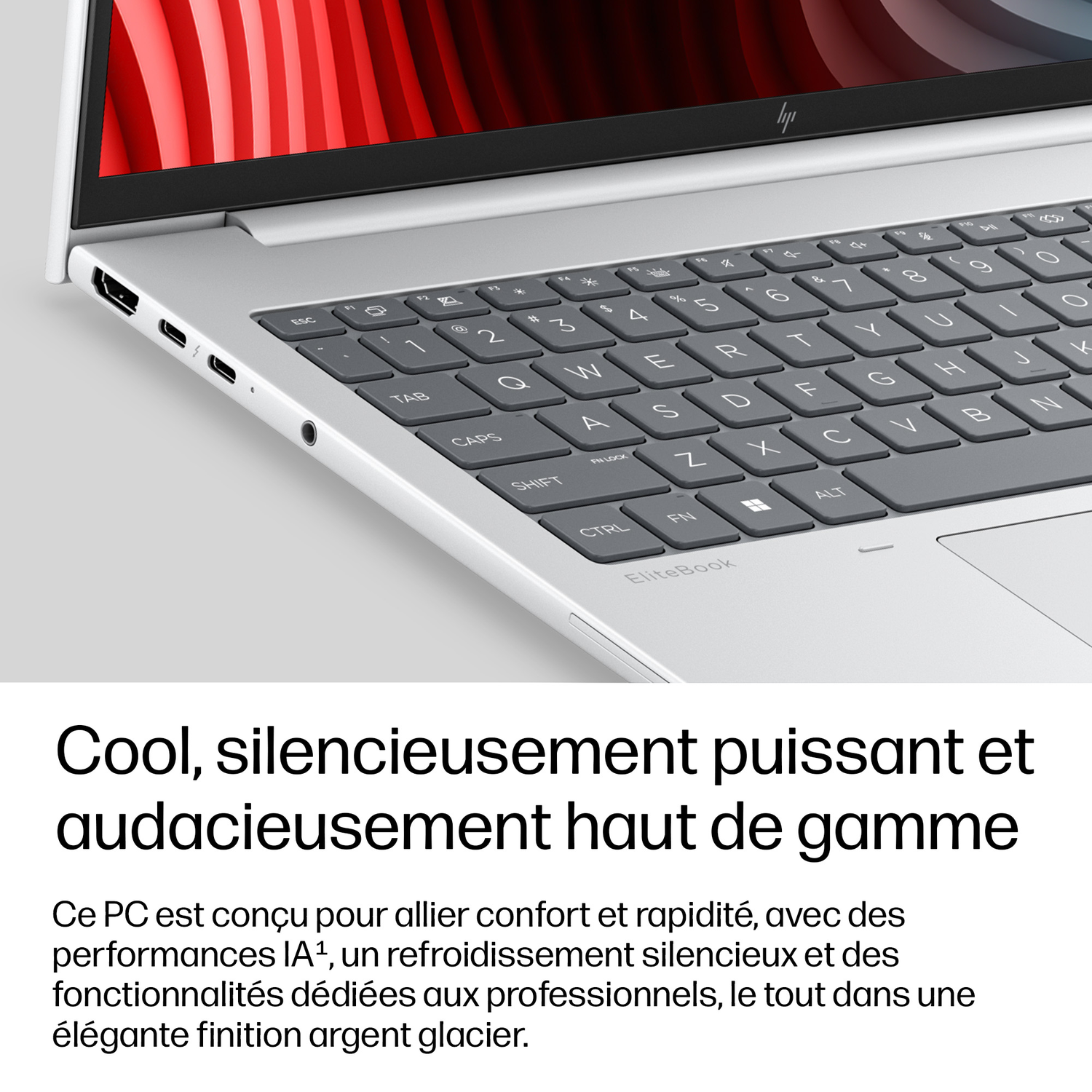 Ordinateur portable argenté avec clavier et ports. Écran affiche des motifs abstraits rouges.