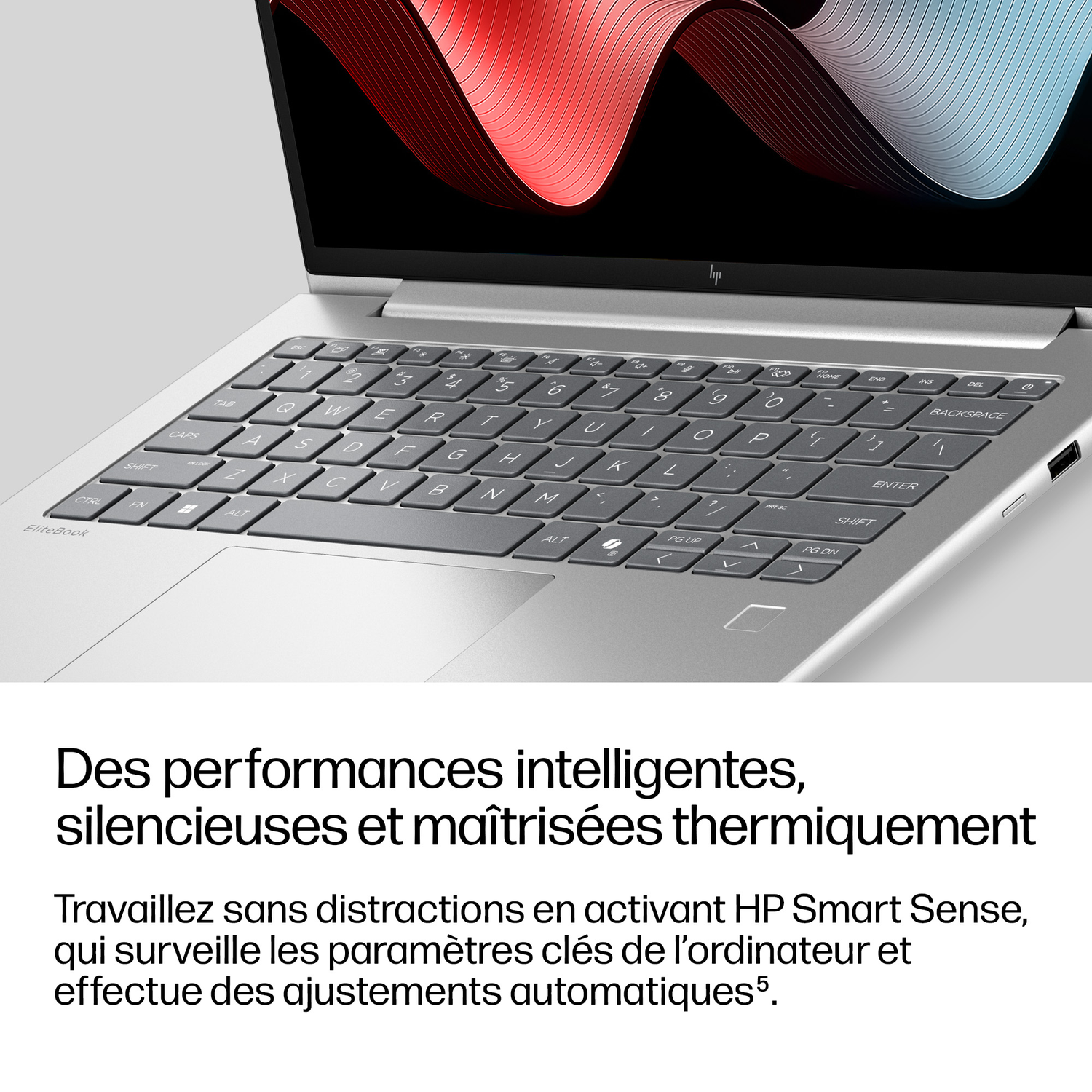 Un ordinateur portable argenté avec clavier et écran affichant un motif abstrait.