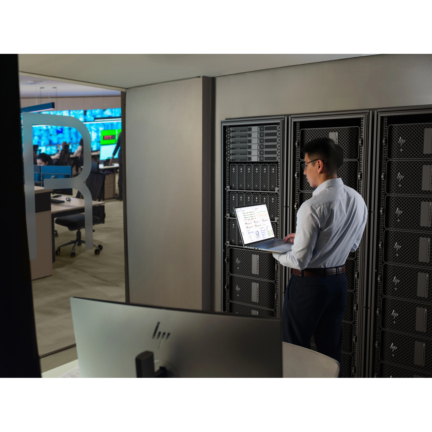 Man met laptop staat voor serverracks in een datacenter.