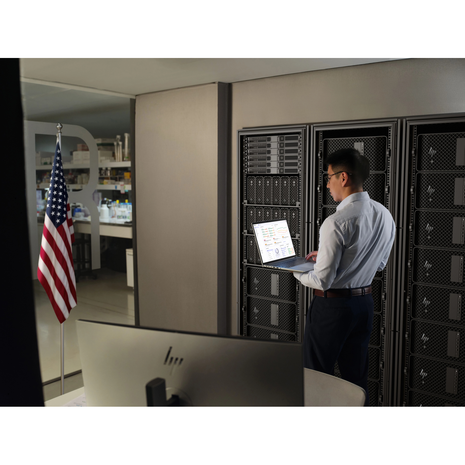 Man met laptop voor serverracks, Amerikaanse vlag op voorgrond.