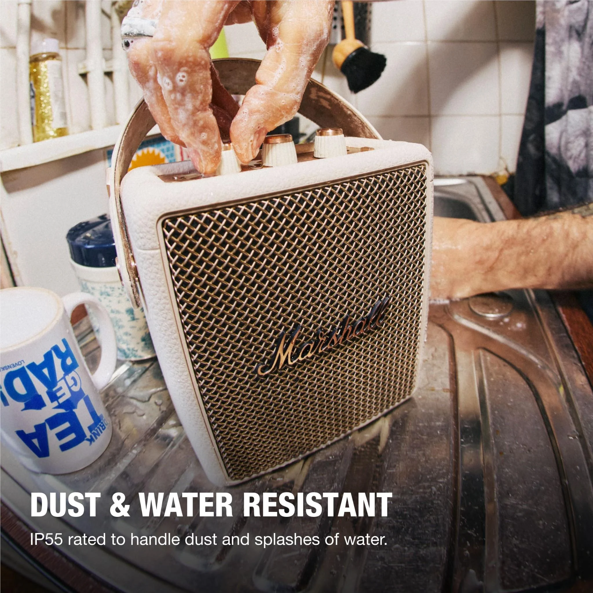 Seifenhände reinigen einen Marshall-Lautsprecher neben einer Tasse und einem Waschbecken.