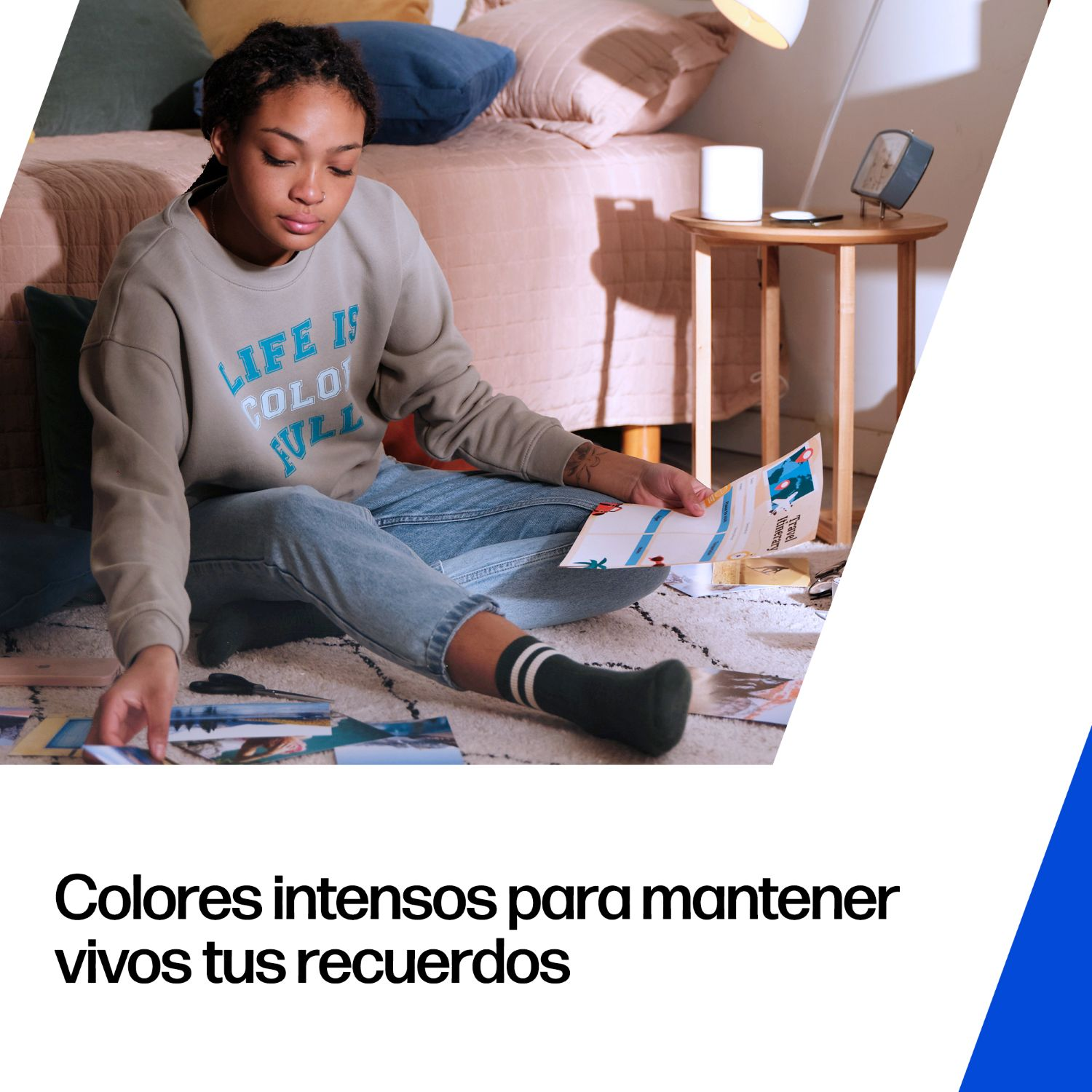 Una joven sentada en una alfombra, ordenando fotos. Viste jeans y un suéter gris.