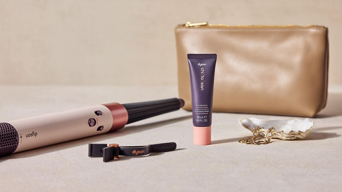 Un styler per capelli Dyson, siero e trousse da cosmetici su un tavolo.