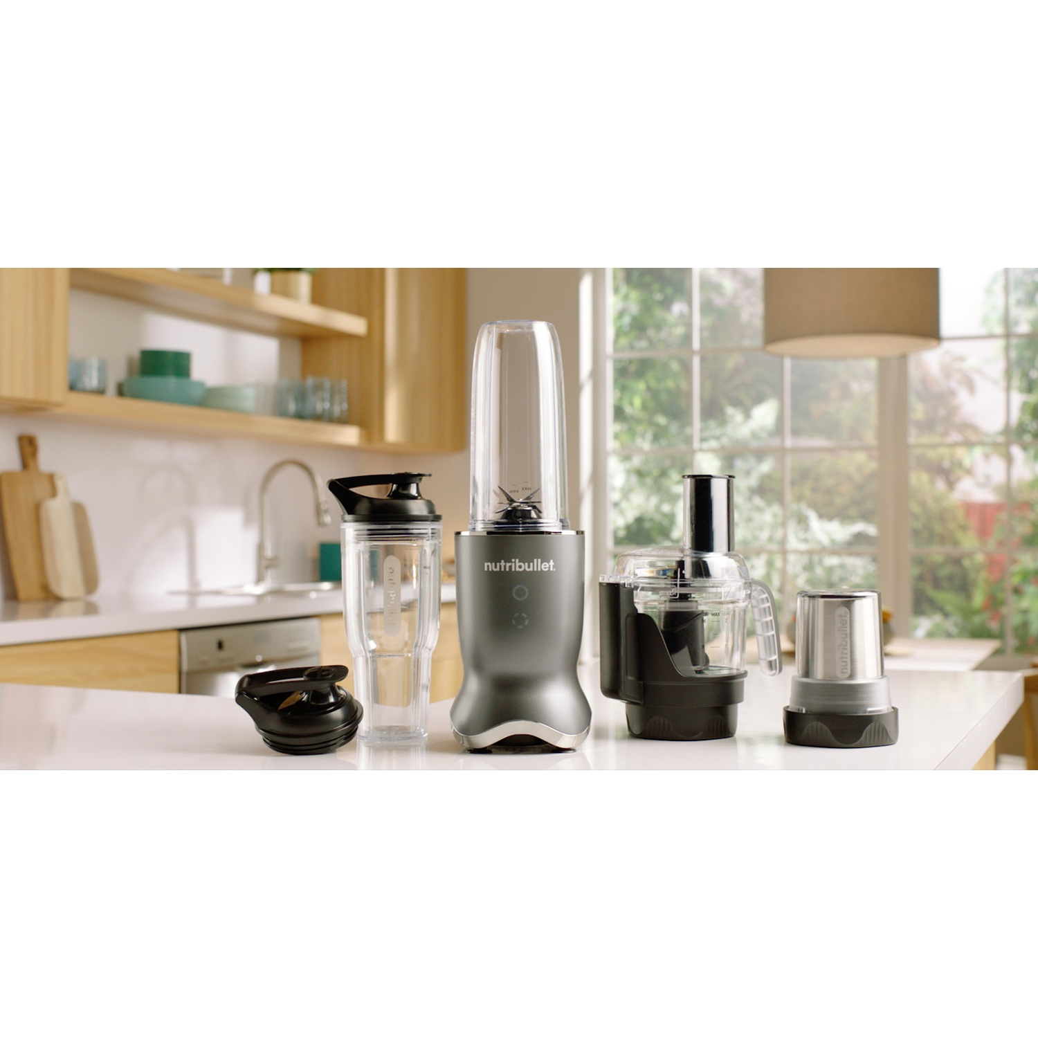Un bancone da cucina con un frullatore Nutribullet grigio, tazza e accessori.