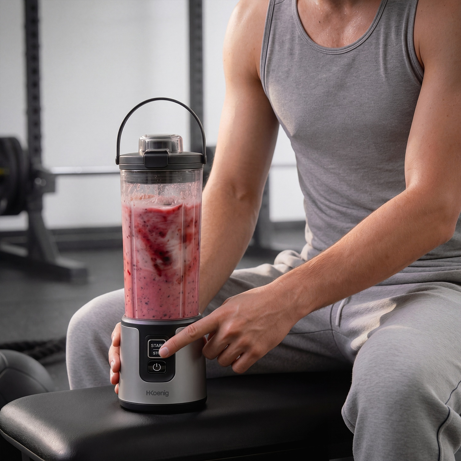 Uomo in palestra preme start su frullatore con frullato di bacche.