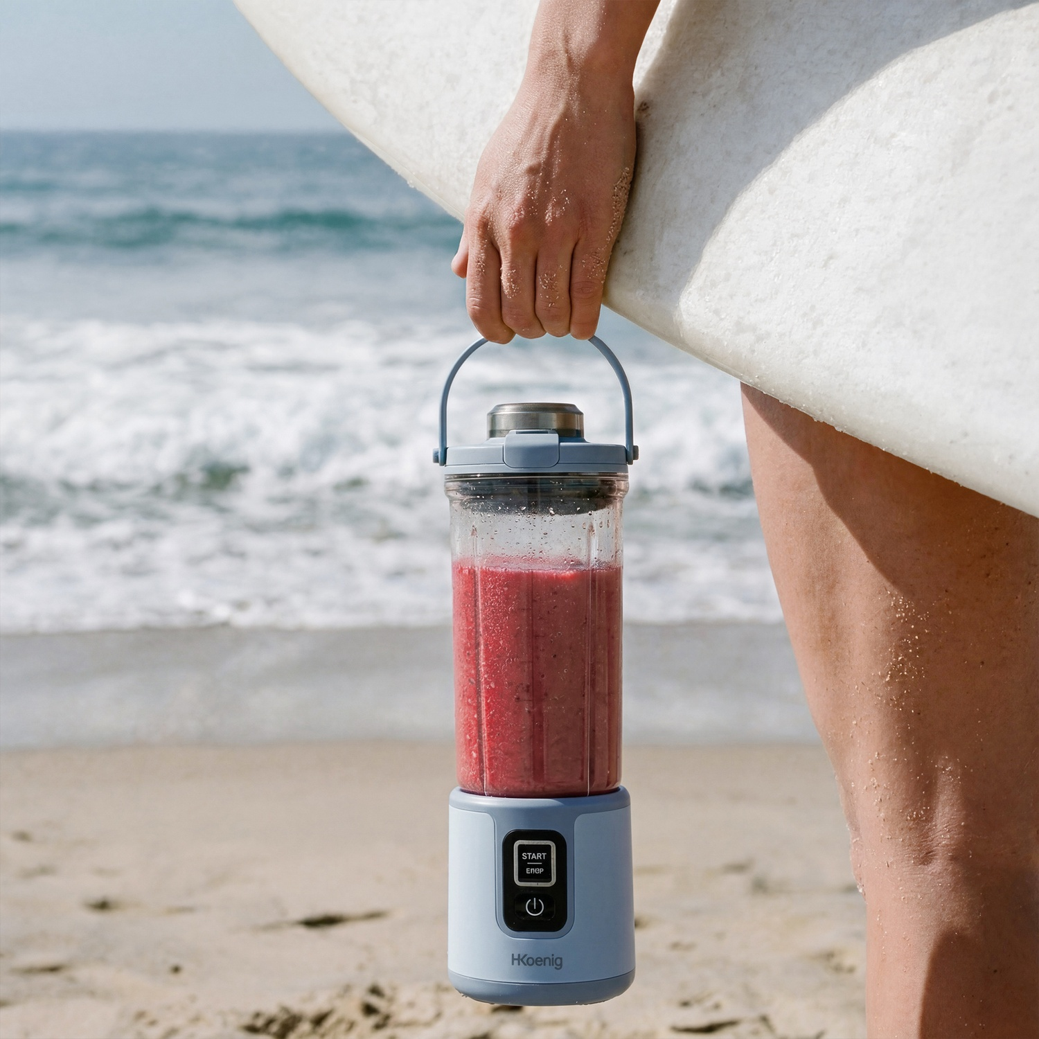 Una persona tiene un frullatore portatile con frullato rosso e una tavola da surf in spiaggia.