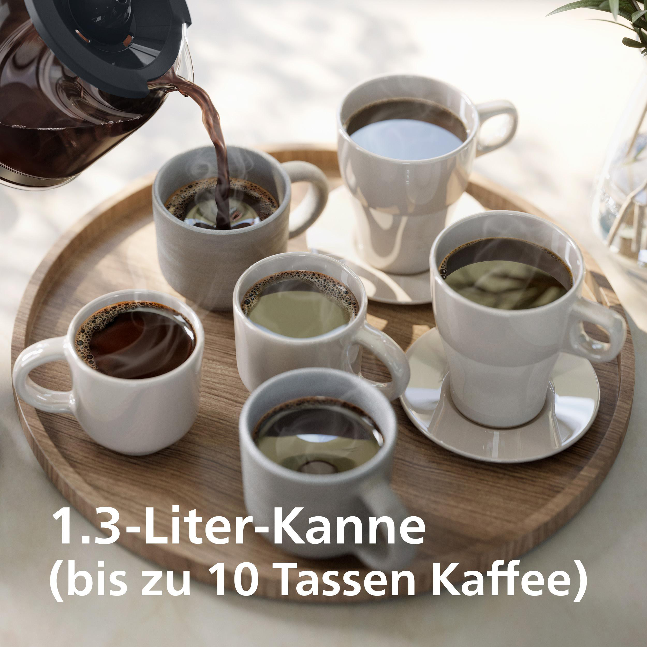 Kaffeekanne schüttet Kaffee in fünf Tassen auf einem Holzteller.