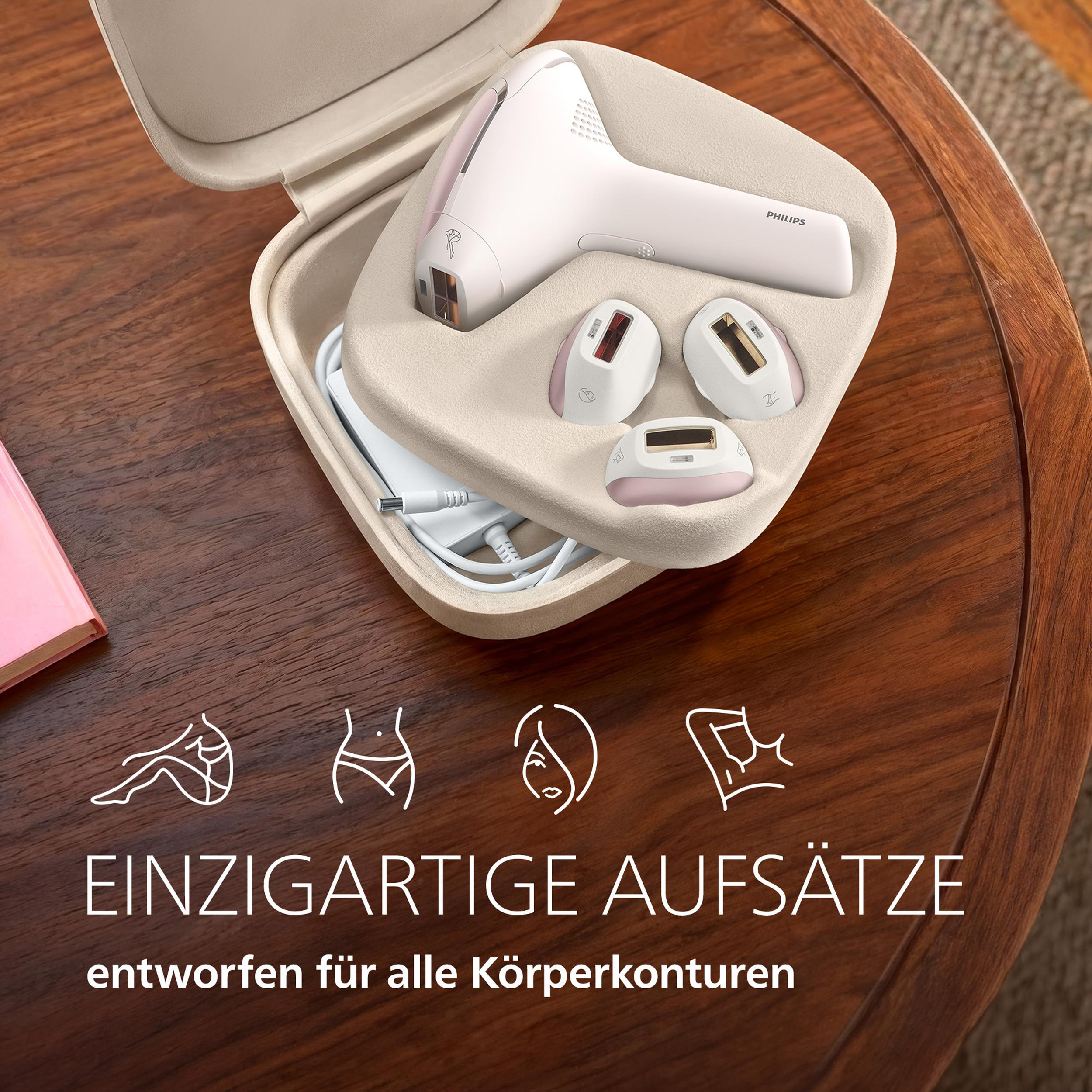 Ein weißer Philips IPL-Haarentferner mit Aufsätzen in einem Koffer auf einem Holztisch.