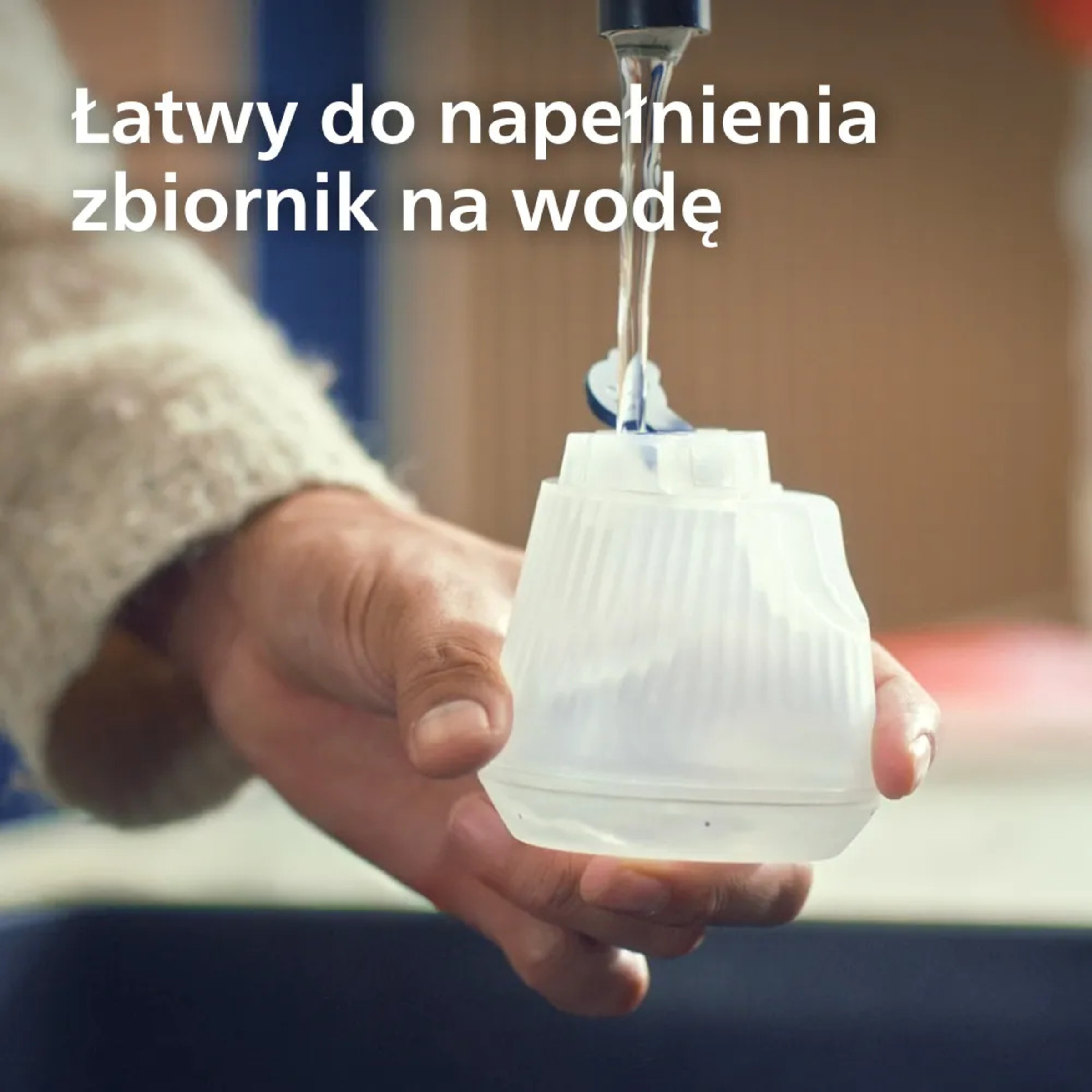 Pojemnik na wodę jest napełniany pod kranem. Trzyma go ręka.