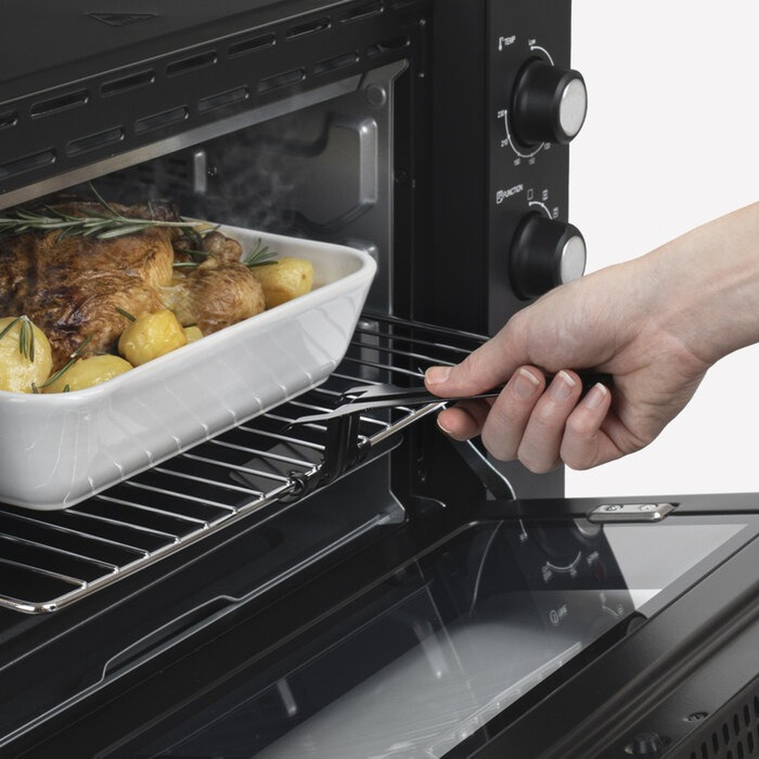 Un pollo arrosto con patate viene tolto dal forno.