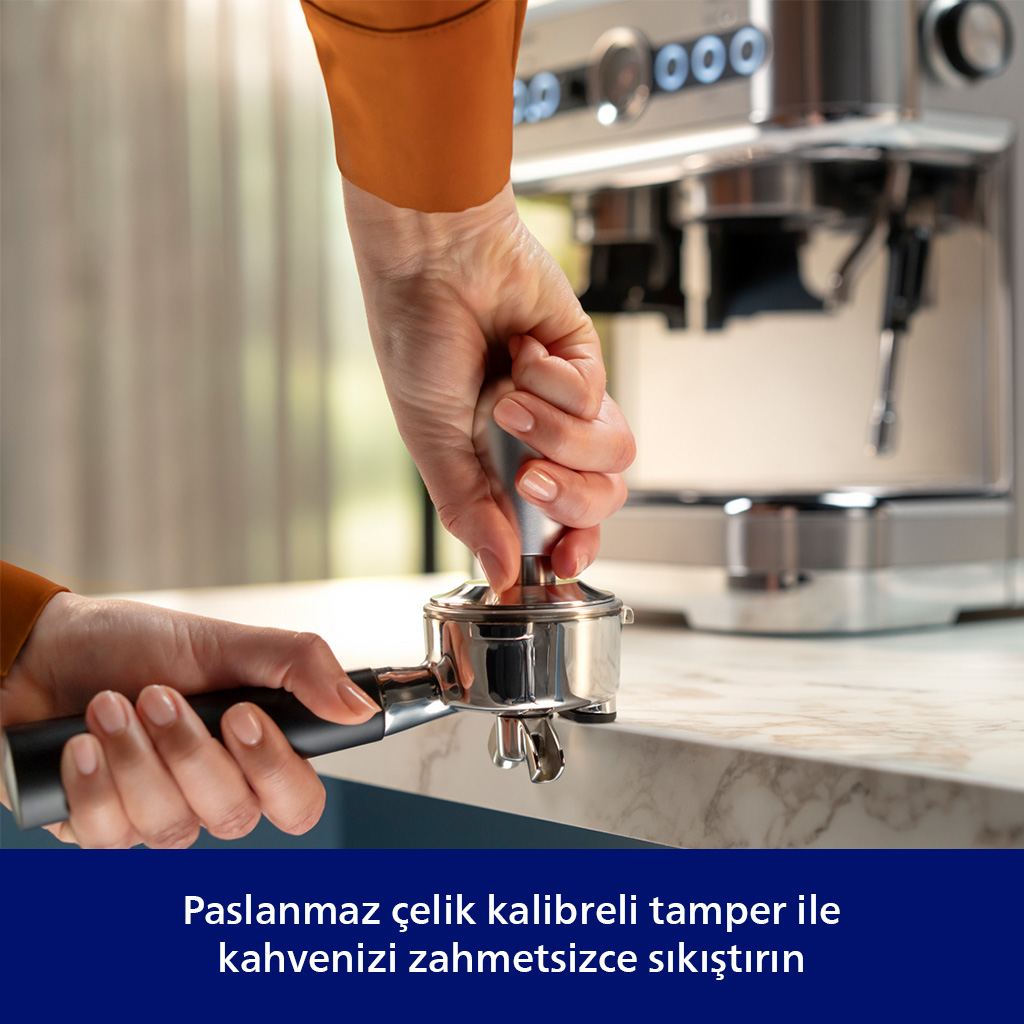 Bir el, tamper ile espresso makinesi portafiltresine kahve tampeliyor.