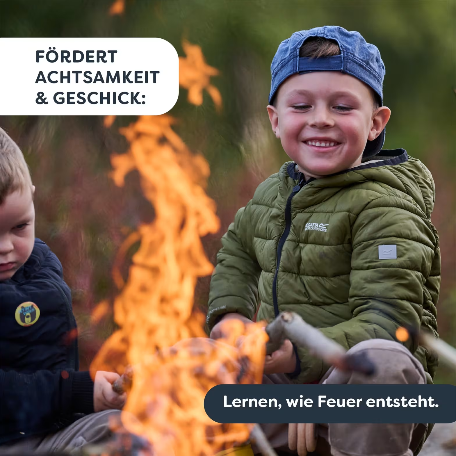 Két fiú ül tábortűz mellett. A jobb oldali fiú mosolyog.
