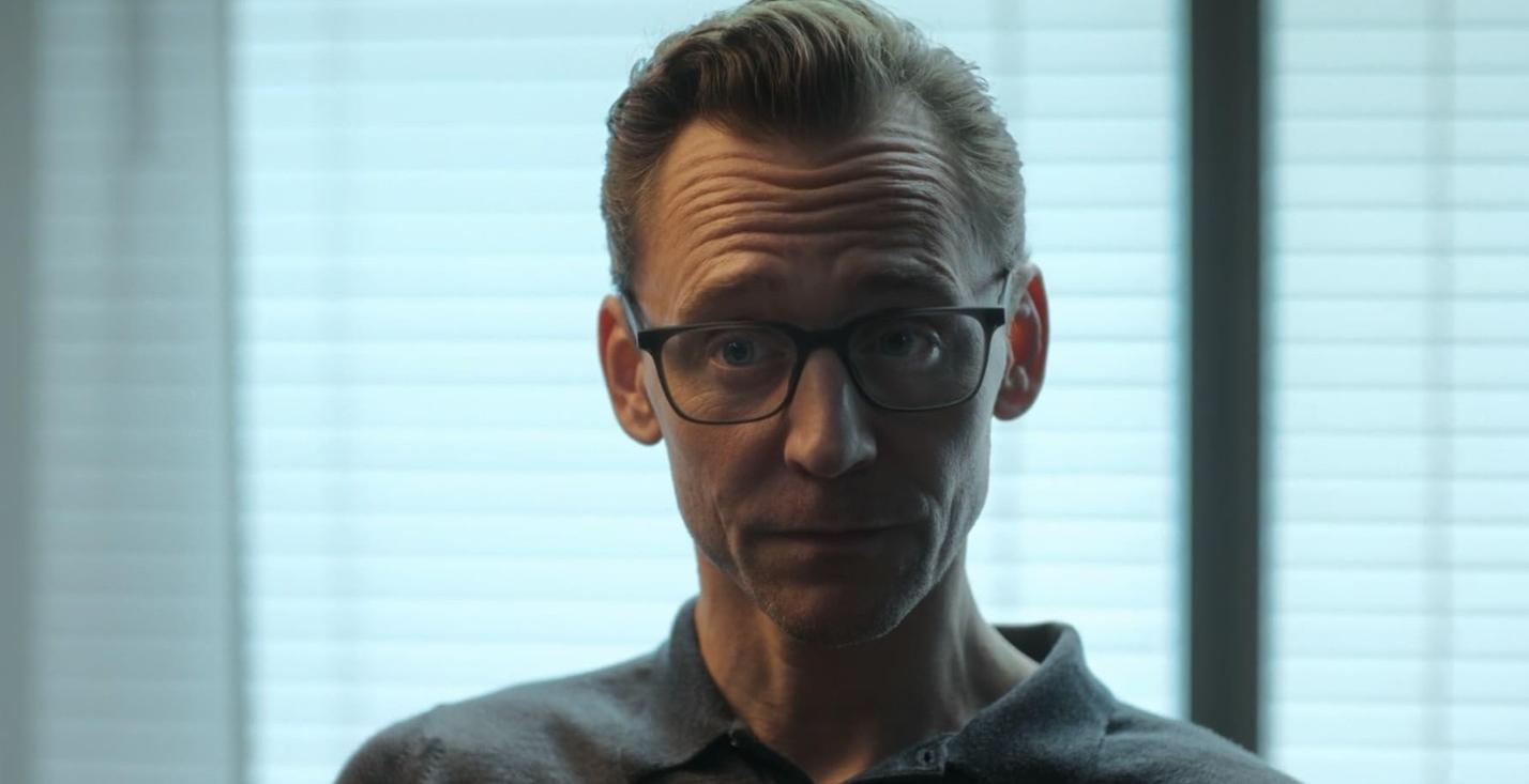 Mann mit Brille schaut nachdenklich, im Hintergrund sind Jalousien.