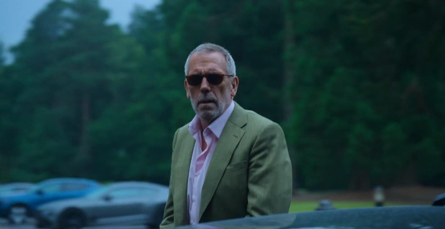 Ein Mann mit Sonnenbrille trägt einen grünen Anzug und ein rosa Hemd.