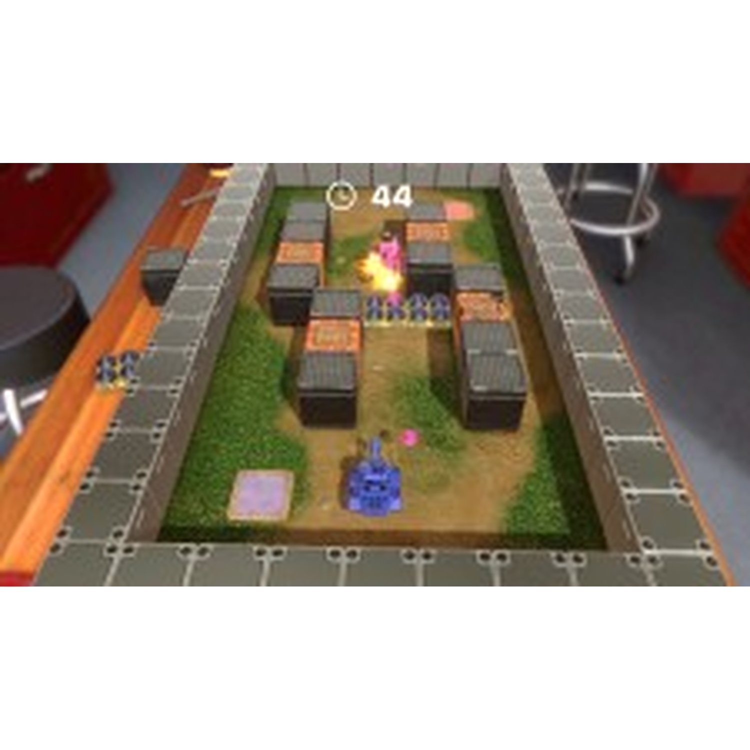 A blue toy tank car drives on a game board with obstacles and grass.