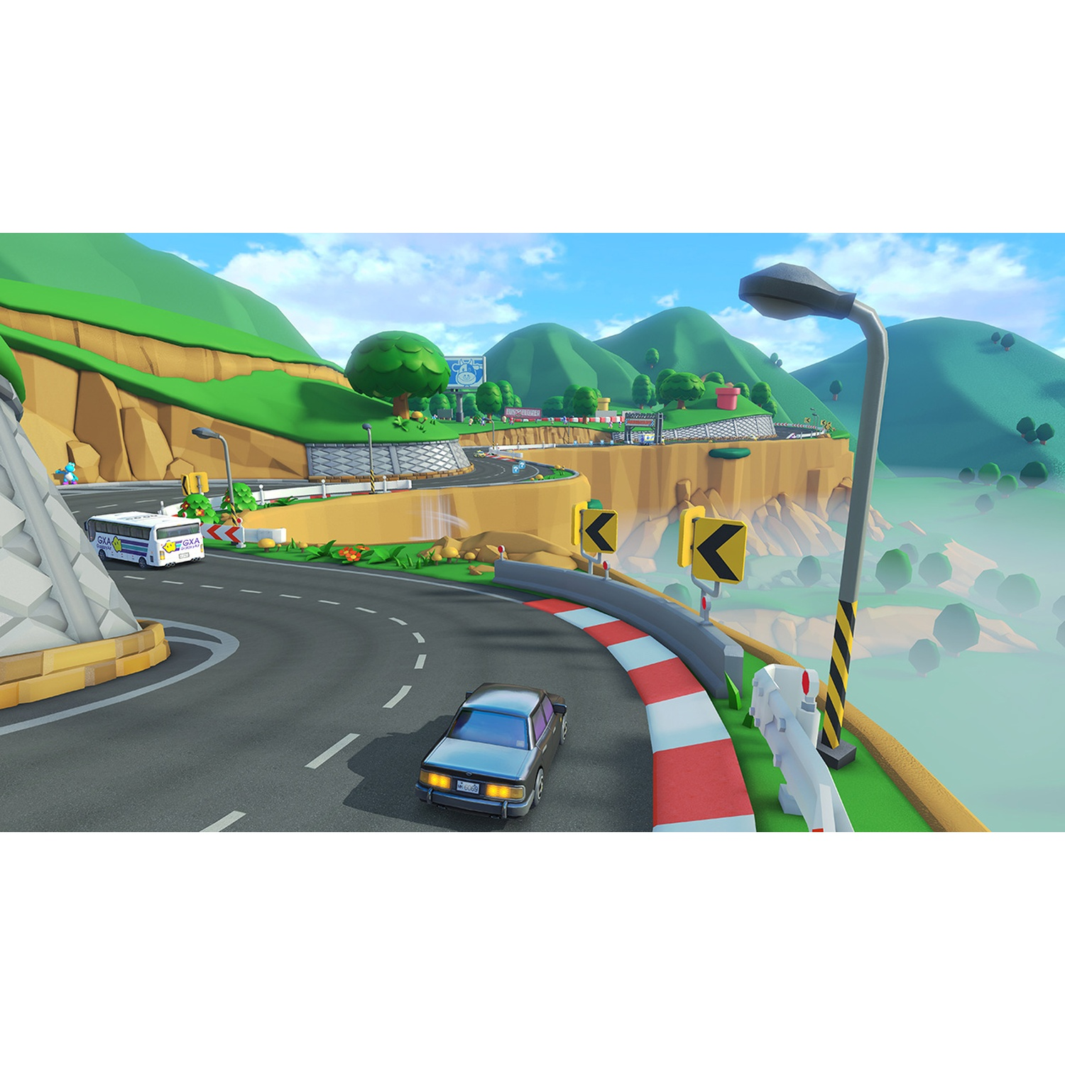 A race track with cars and bus, mountainous landscape, blue sky.