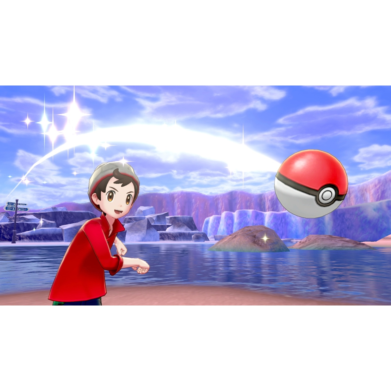 A boy in red throws a pokeball near a body of water with purple mountains.