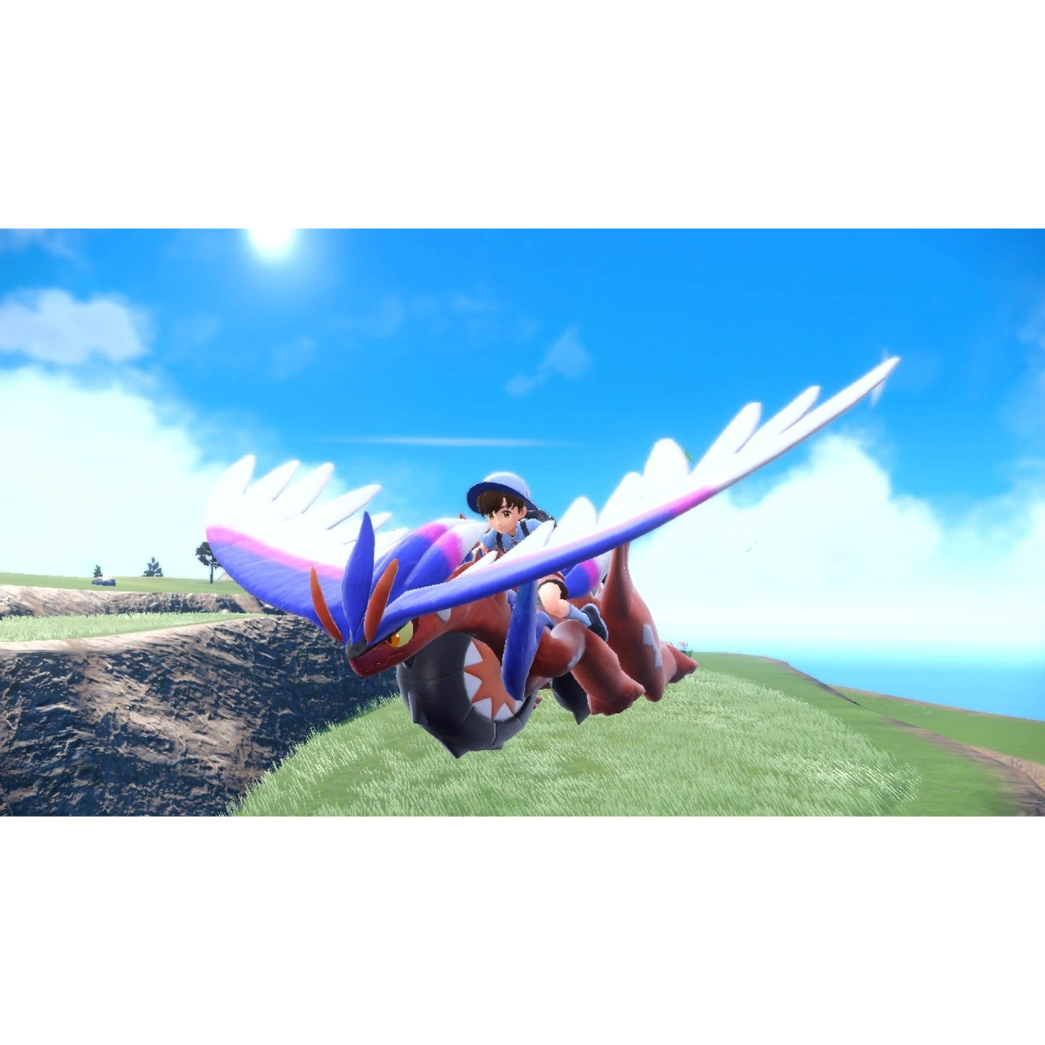 A boy rides a red and blue dragon with white wings over a green landscape.