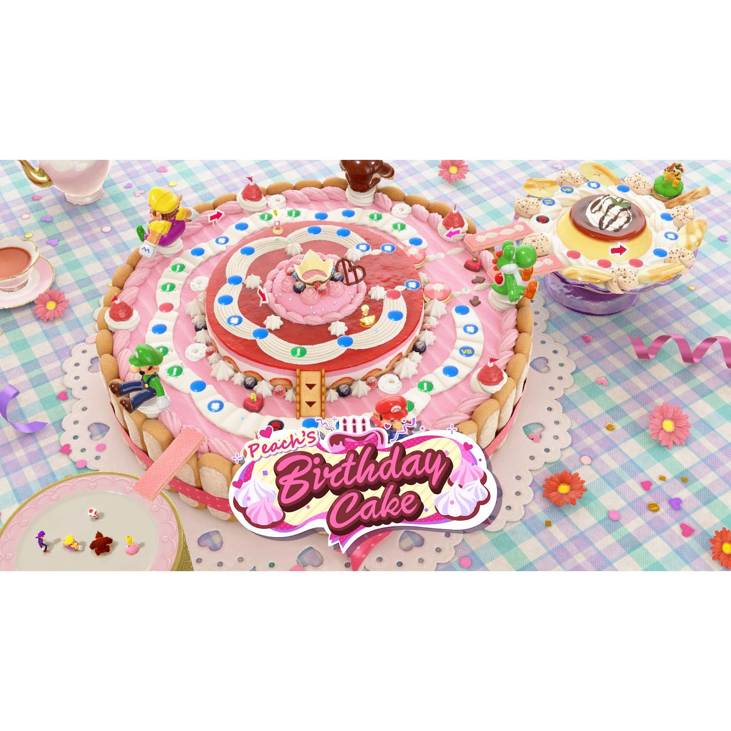 A Mario birthday cake with game characters, sweets, and a teacup on a checkered tablecloth.