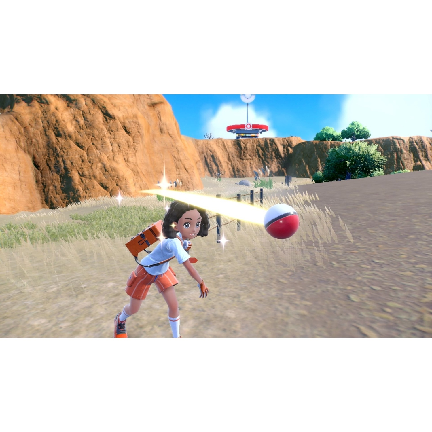 A girl throws a red and white ball in a desert landscape.