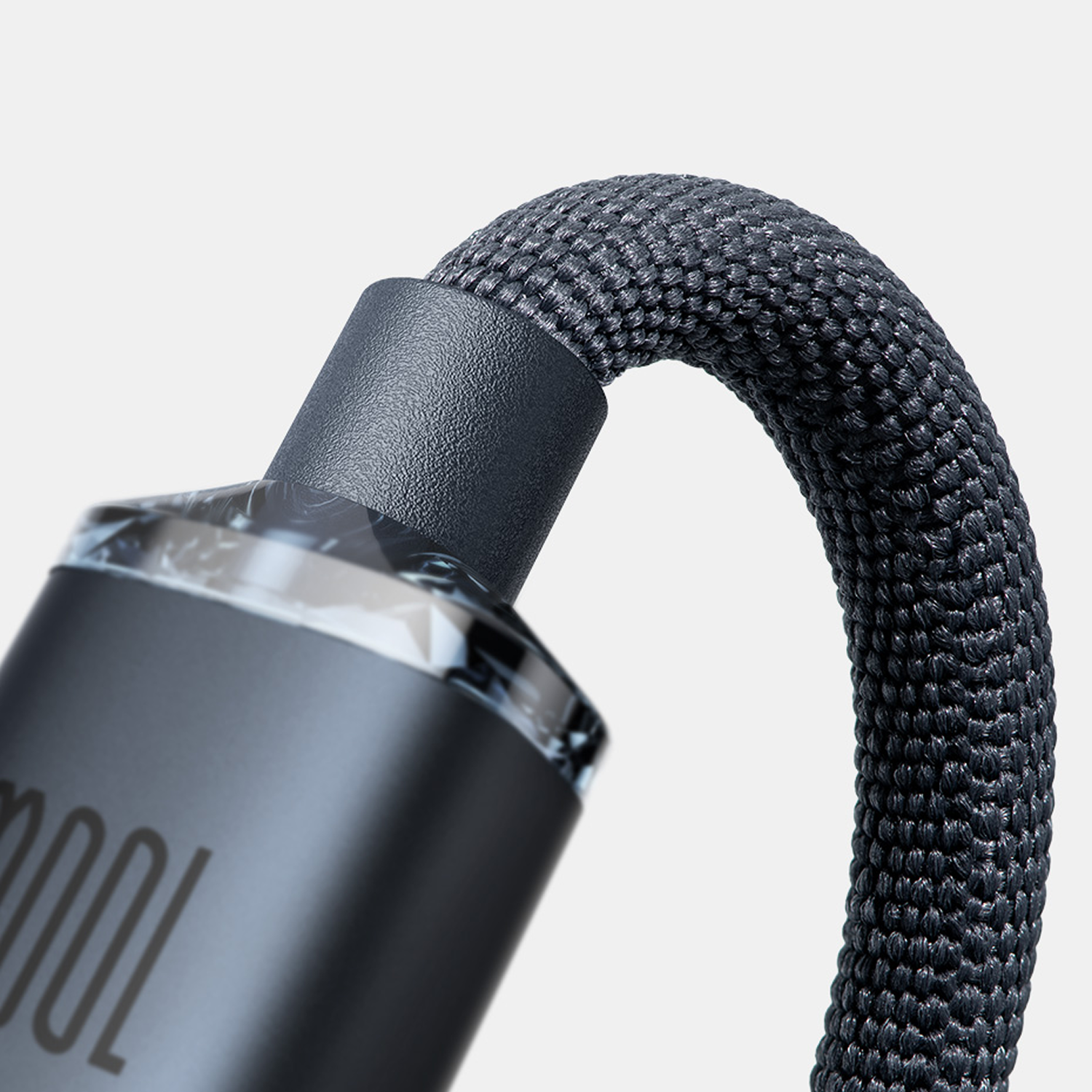 Un cable tejido oscuro se curva sobre un cilindro gris brillante con texto.