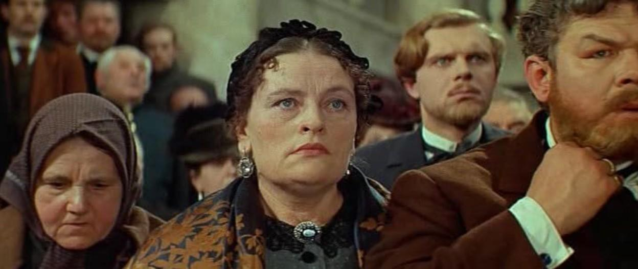 Eine Gruppe Menschen in historischer Kleidung, die Frau in der Mitte trägt eine Brosche.