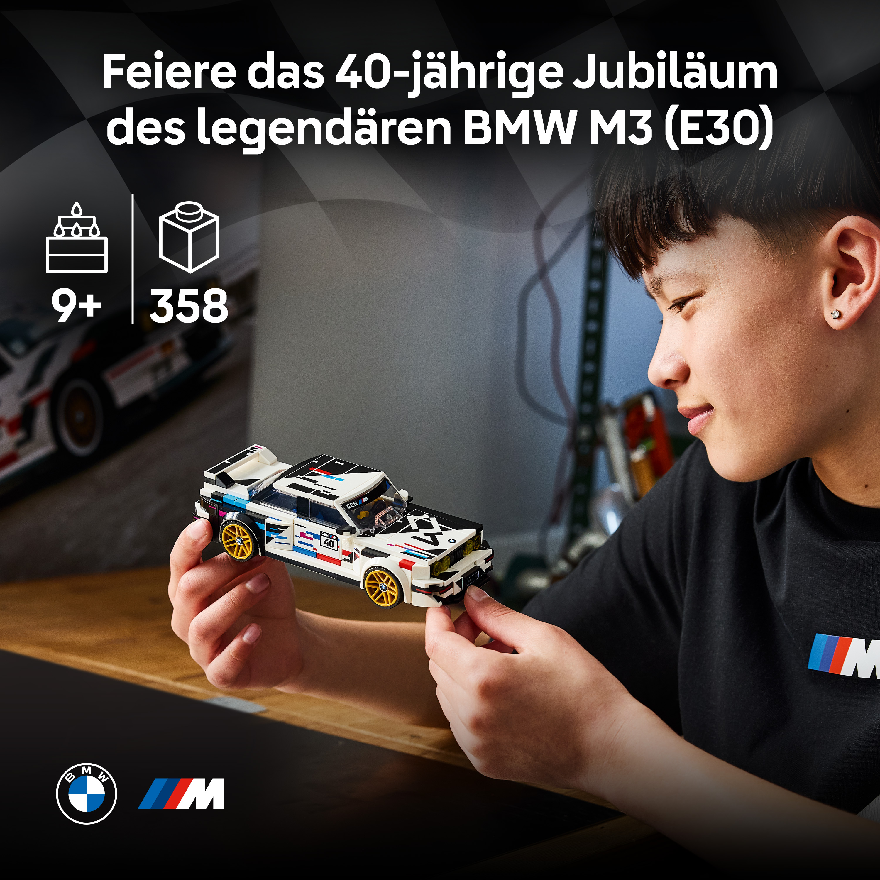 Ein Junge hält ein weißes LEGO BMW M3 (E30) Modellauto mit bunten Aufklebern.