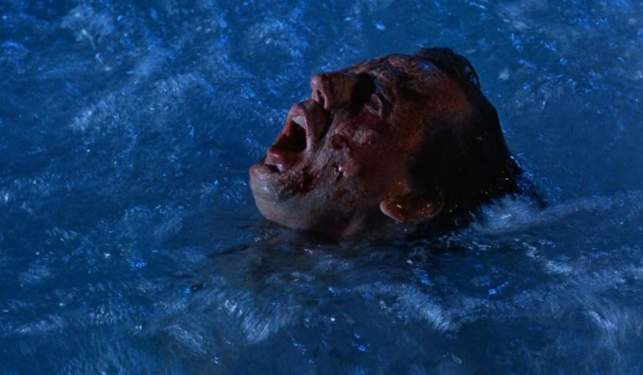 Ein Mann mit blutigem Gesicht schreit in blauem Wasser.