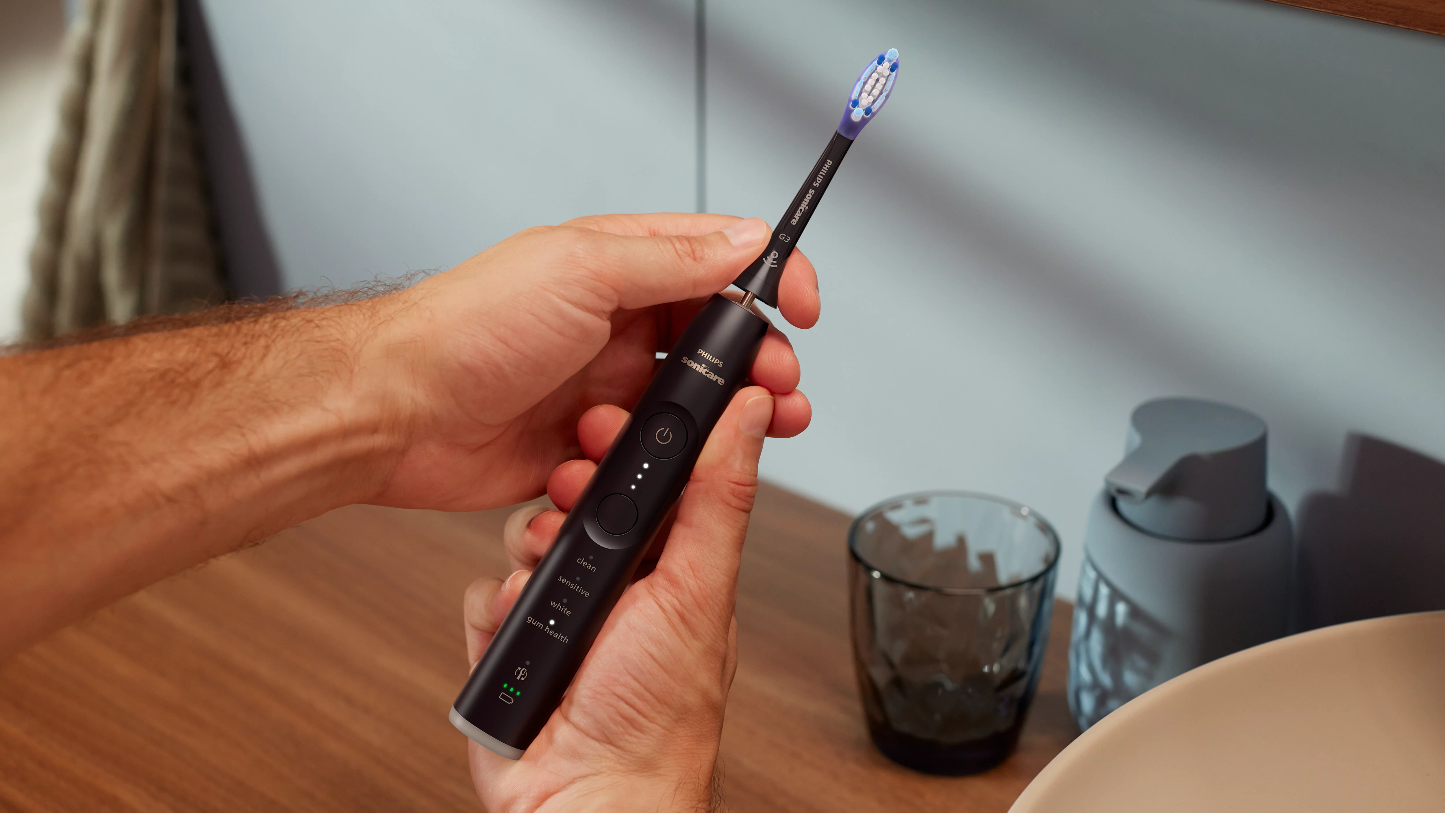 Eine Hand hält eine schwarze elektrische Zahnbürste mit blau-weißem Bürstenkopf.