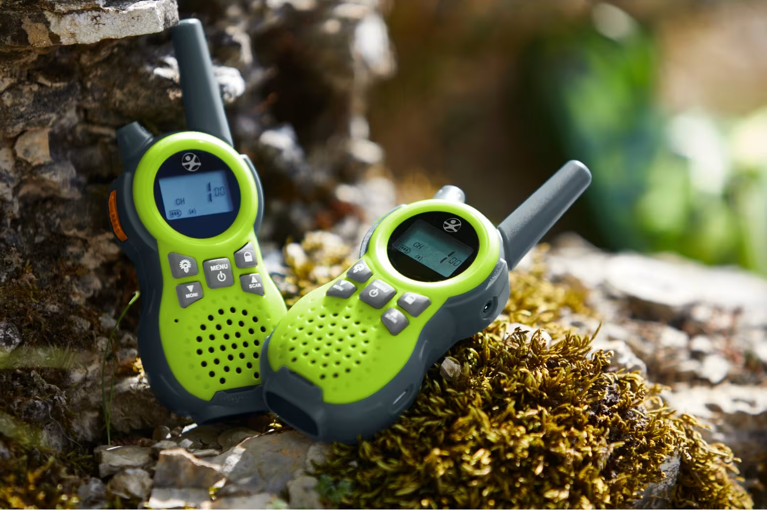 Két lime zöld és szürke walkie-talkie ül mohás sziklákon.