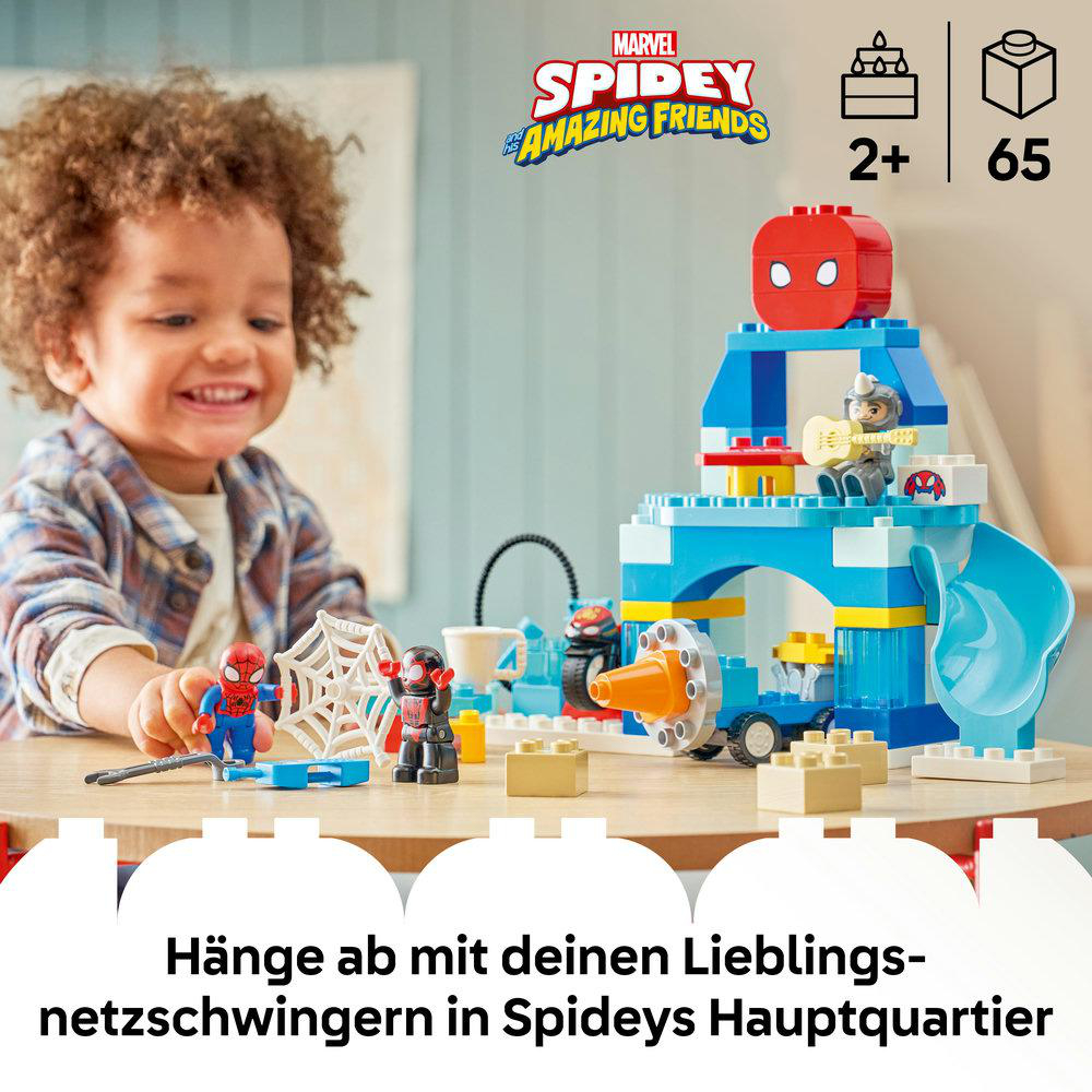 Ein lächelnder Junge spielt mit Spidey und Miles Morales LEGO-Figuren und einem Spidey-Hauptquartier-Spielset.