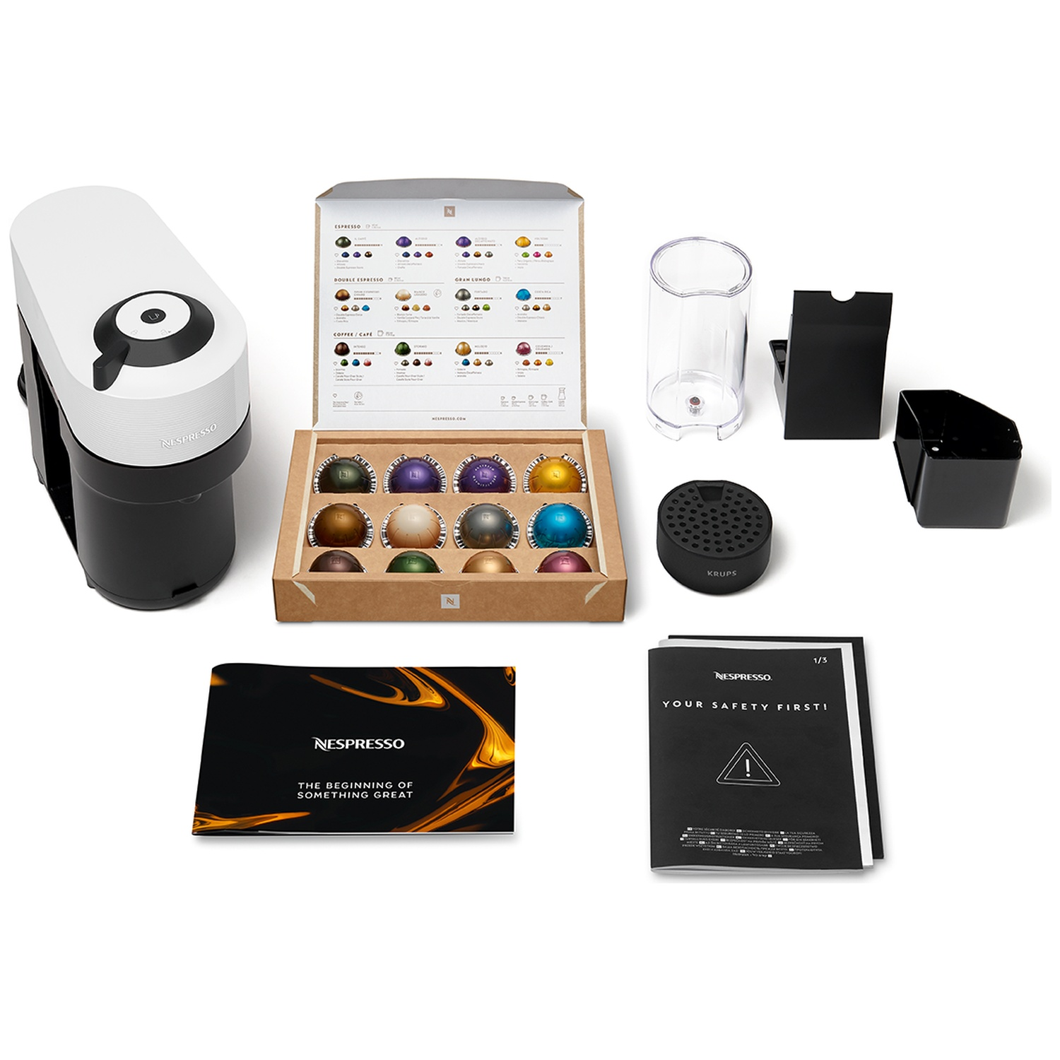 Nespresso coffee machine with capsules, manual, and accessories on a white background.