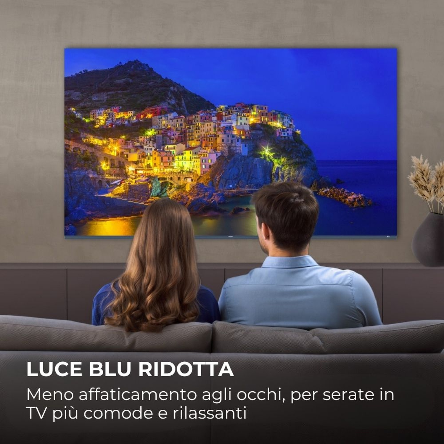 Una coppia guarda un borgo costiero illuminato di notte.