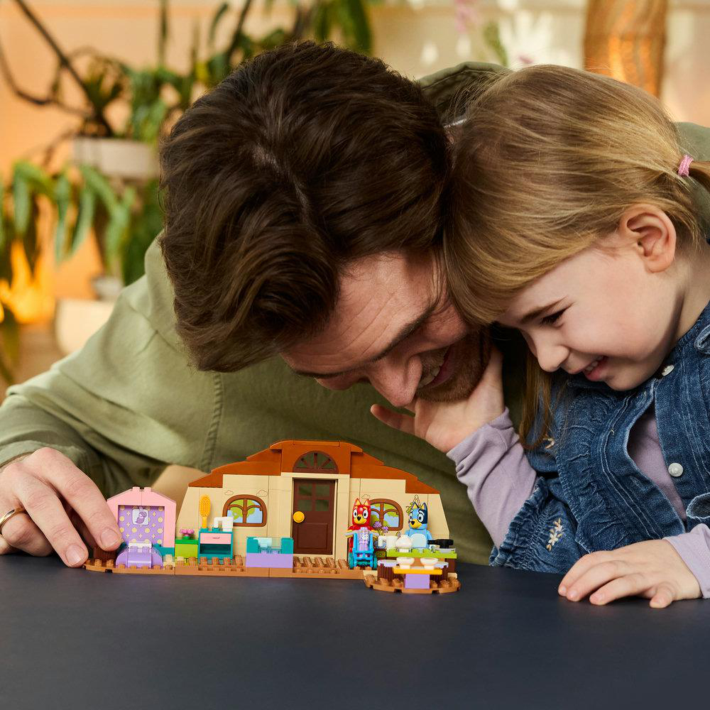 Ein Mann und ein kleines Mädchen bauen ein Lego-Haus mit Figuren.