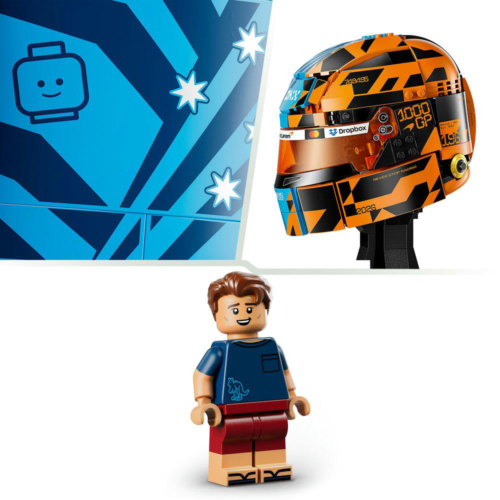 Eine Lego-Figur steht vor einem Lego-Rennhelm und einer blauen Kiste mit Sternenmustern.