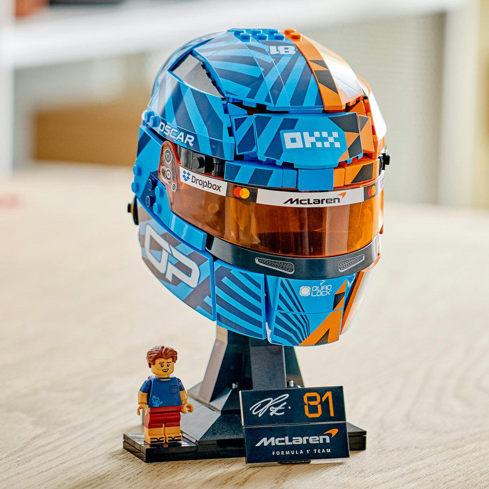 Ein Lego-Helm-Modell in Blau und Orange mit einem Minifiguren-Fahrer und einem Ständer.