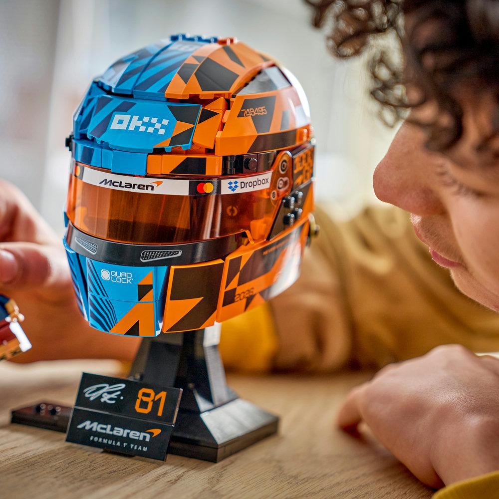 Ein Mann betrachtet einen Lego-Helm in Blau und Orange mit McLaren-Logo.