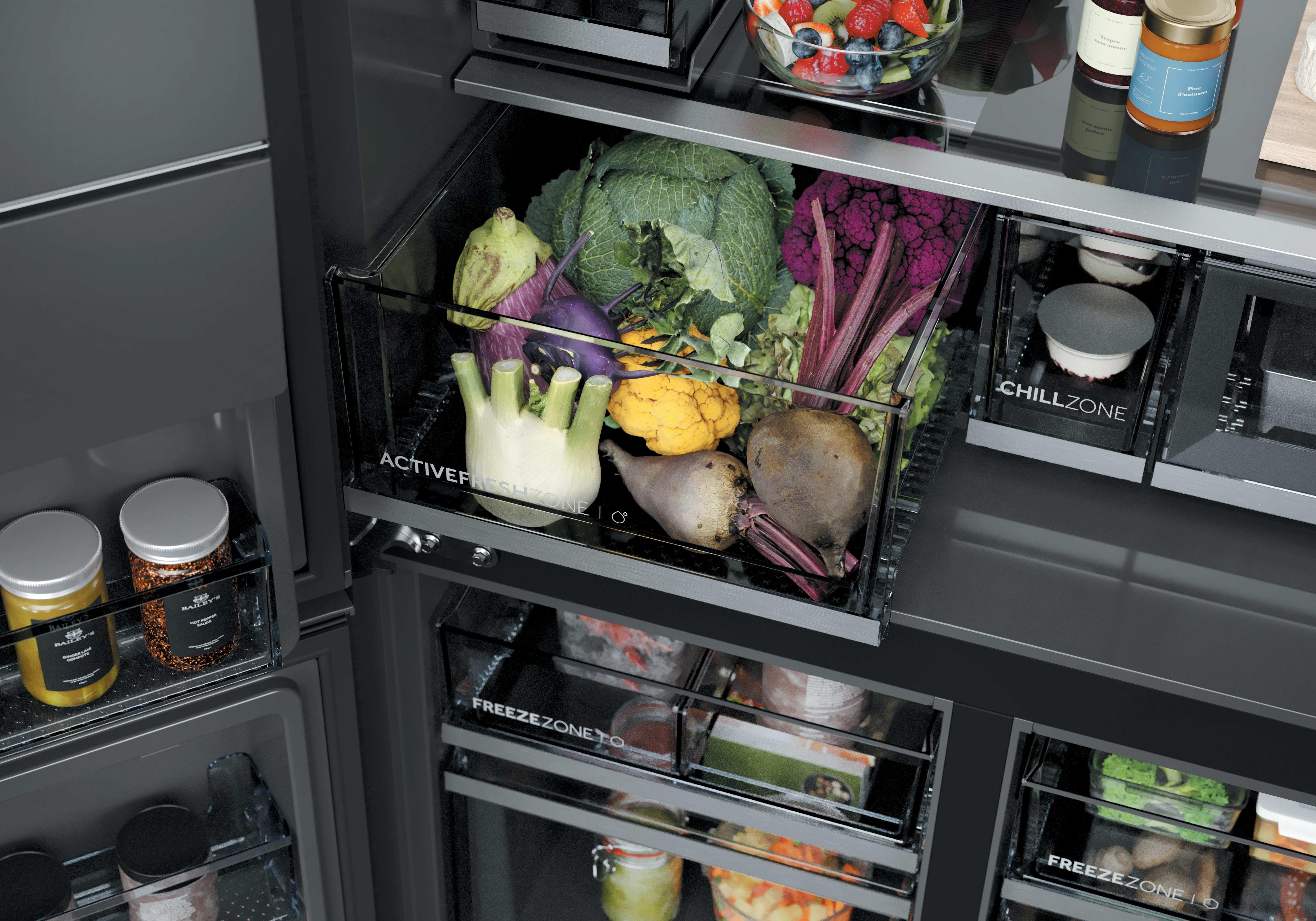 Un refrigerador abierto con cajones llenos de frutas y verduras.