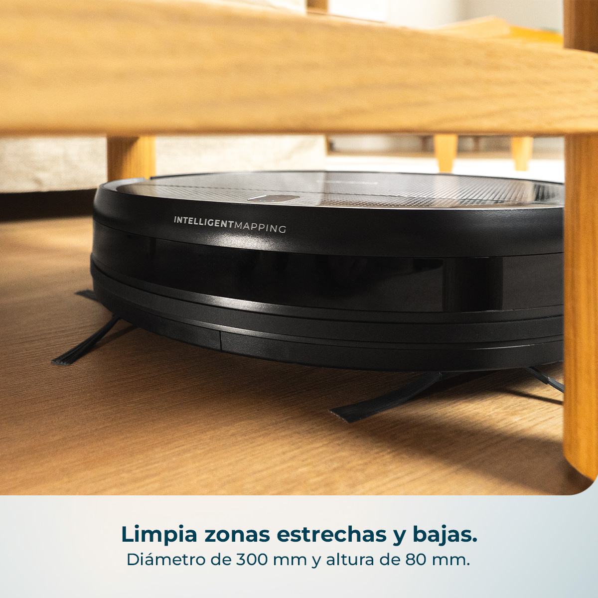 Un robot aspirador negro con "INTELLIGENTMAPPING" limpia bajo una silla de madera.