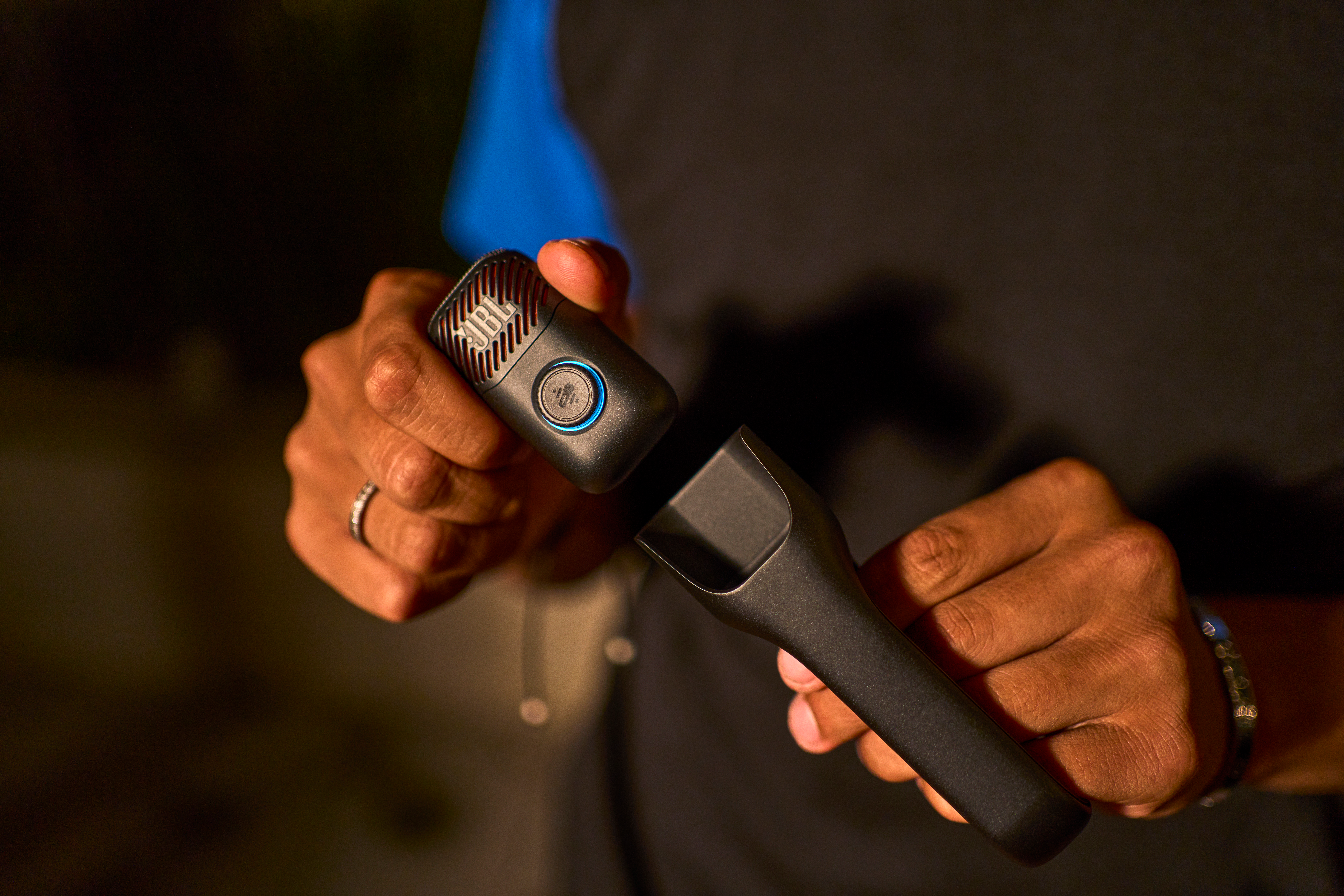 Personne tenant un microphone JBL avec lumière bleue. Gros plan.