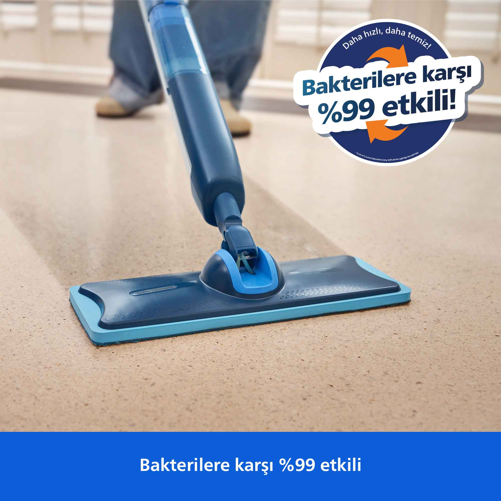 Mavi bir sprey paspas zemini temizliyor. Bir daire 'Bakterilere karşı %99 etkili' diyor.