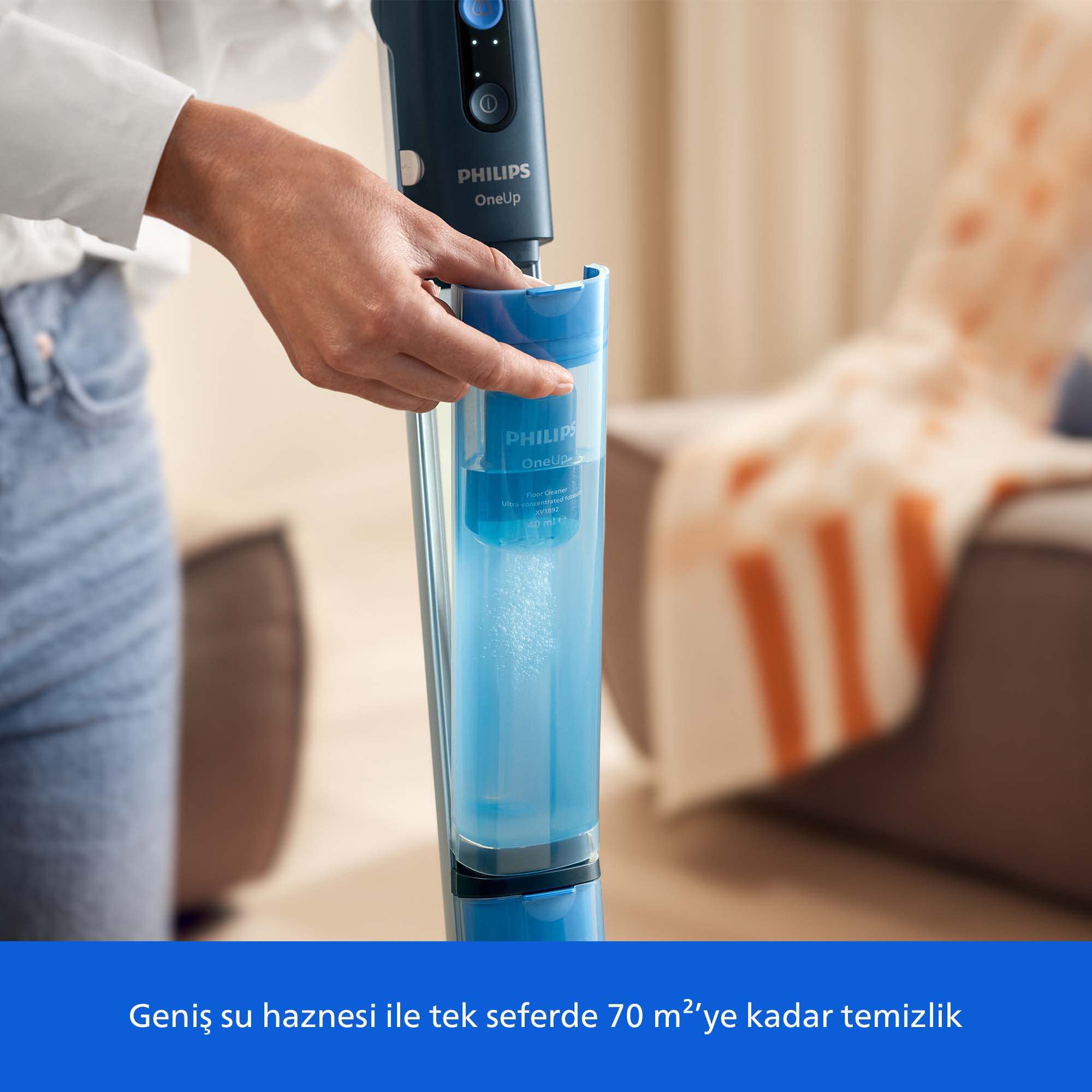 Bir el Philips elektrikli süpürge için mavi su haznesini dolduruyor.
